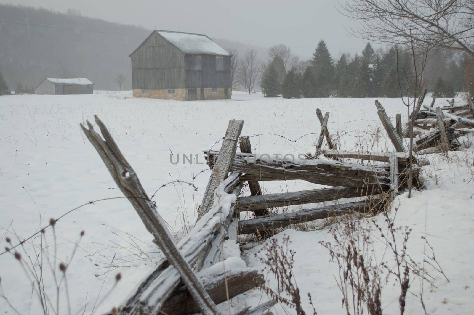 An ontario bank barn with split cedar rail fence in the snow in winter