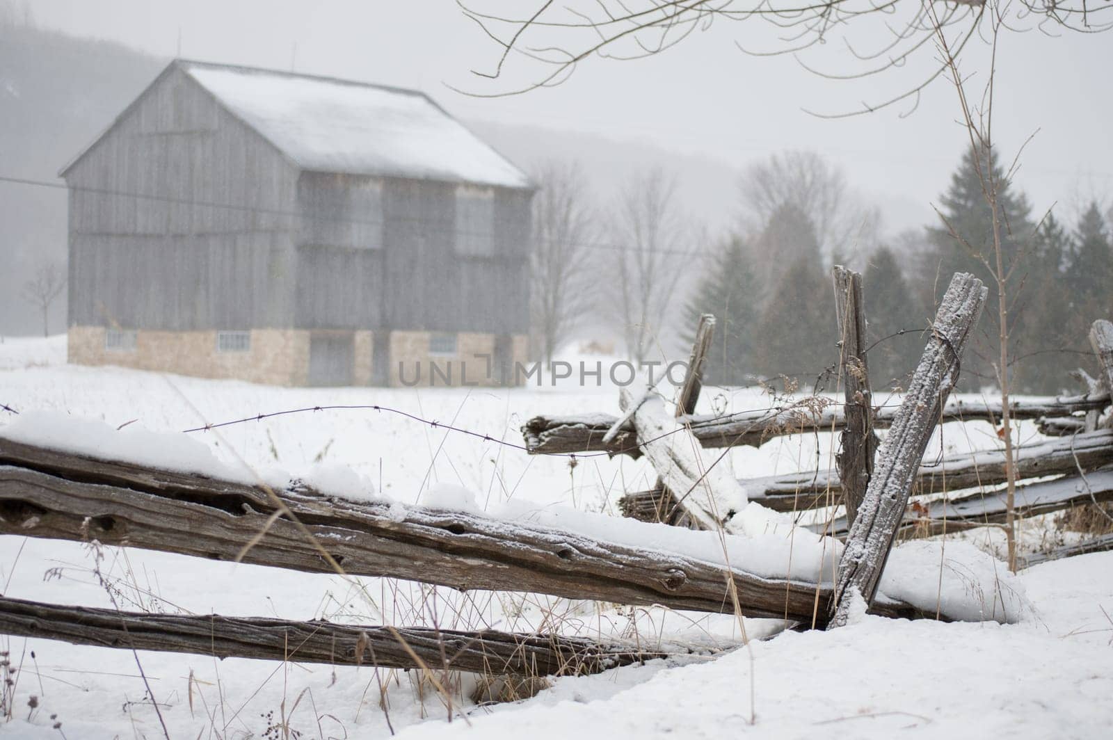An ontario bank barn with split cedar rail fence in the snow in winter