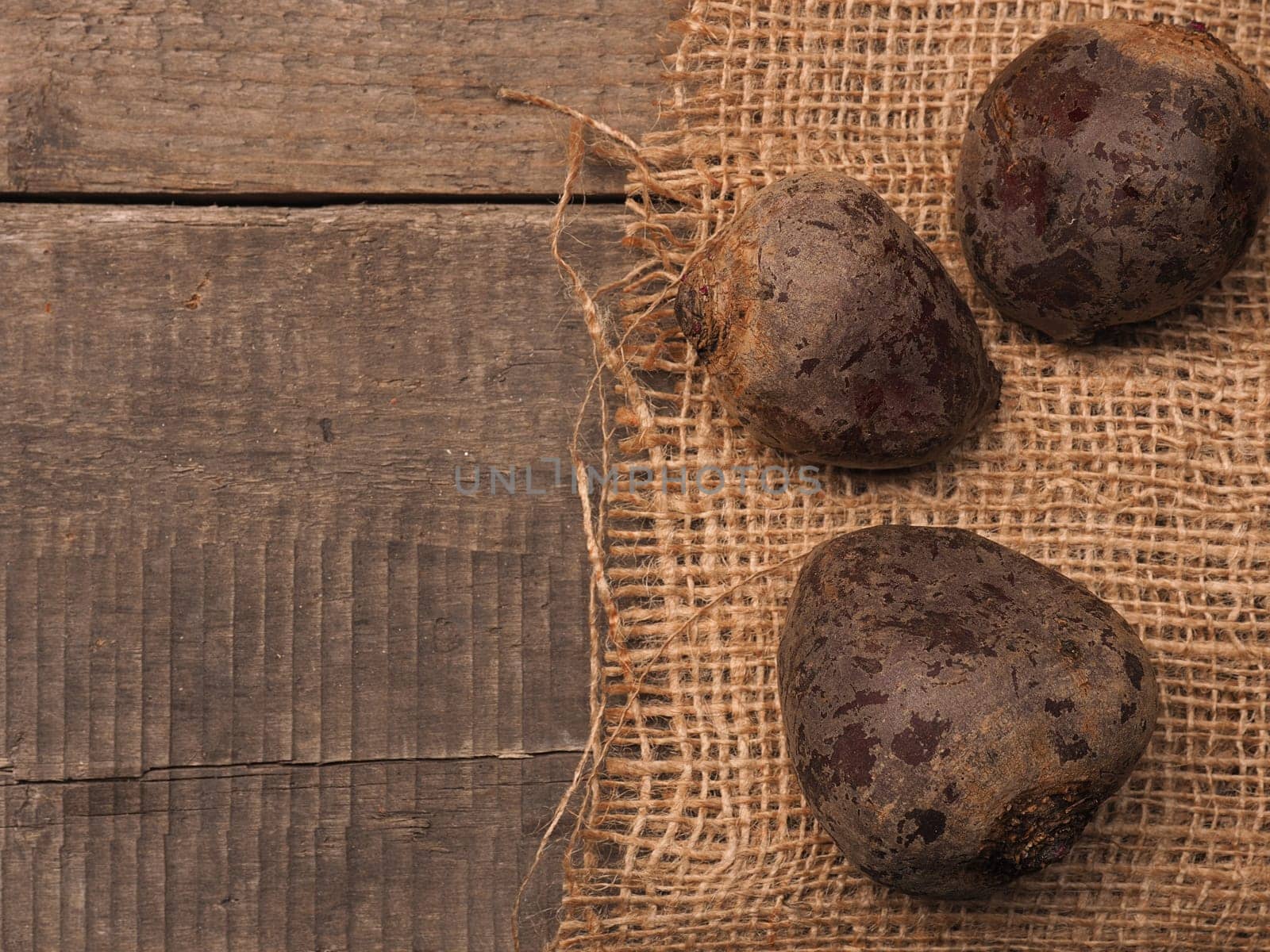 Three organic beet root on burlap with a wooden background