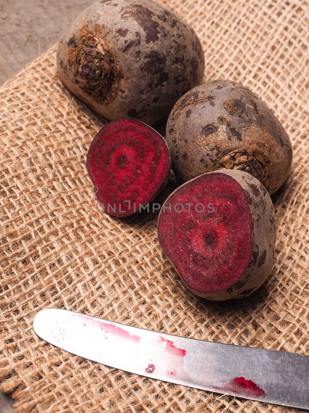 Beet root on burlap and wooden table with an old knife