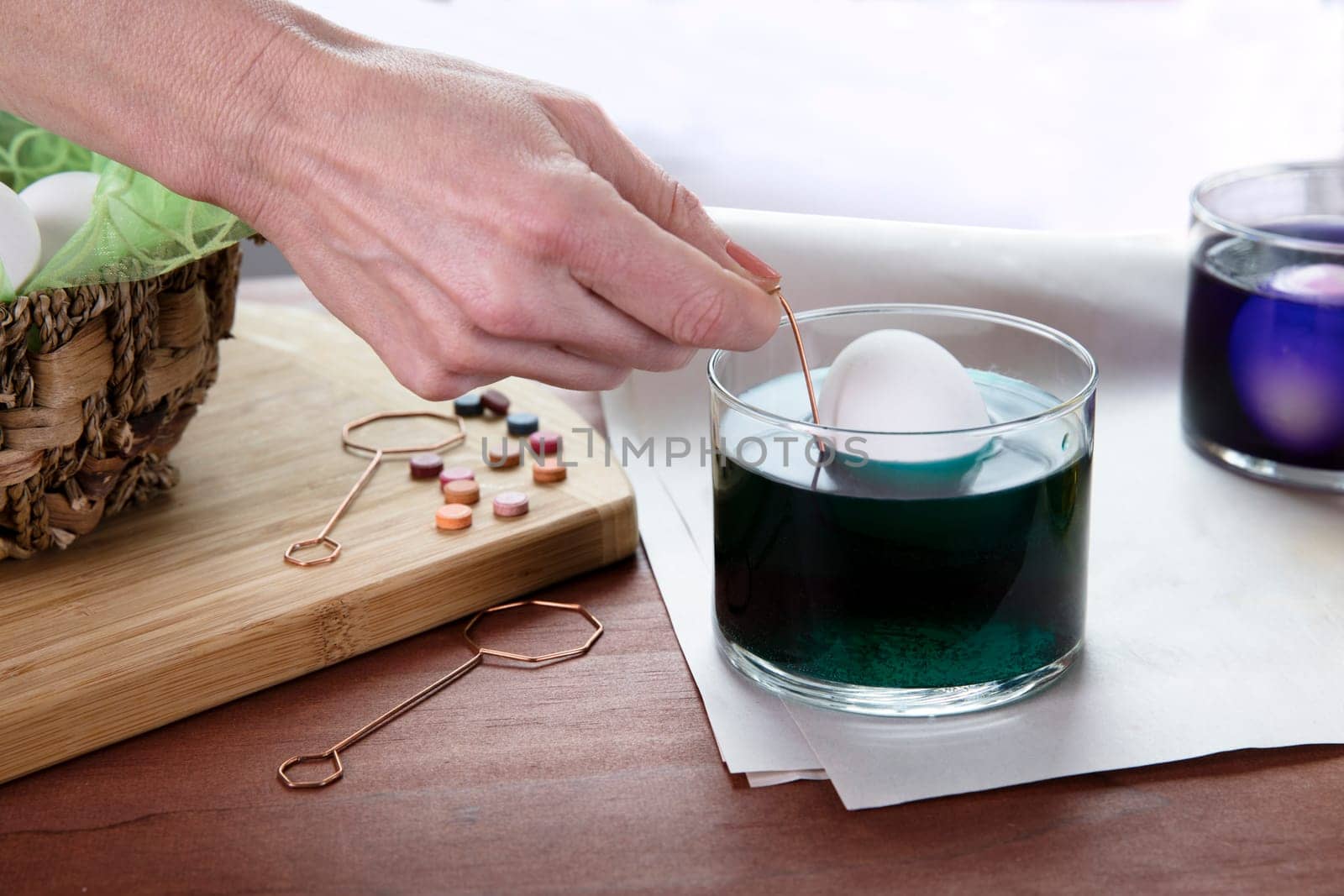 White egg being dipped into green dye for Easter.