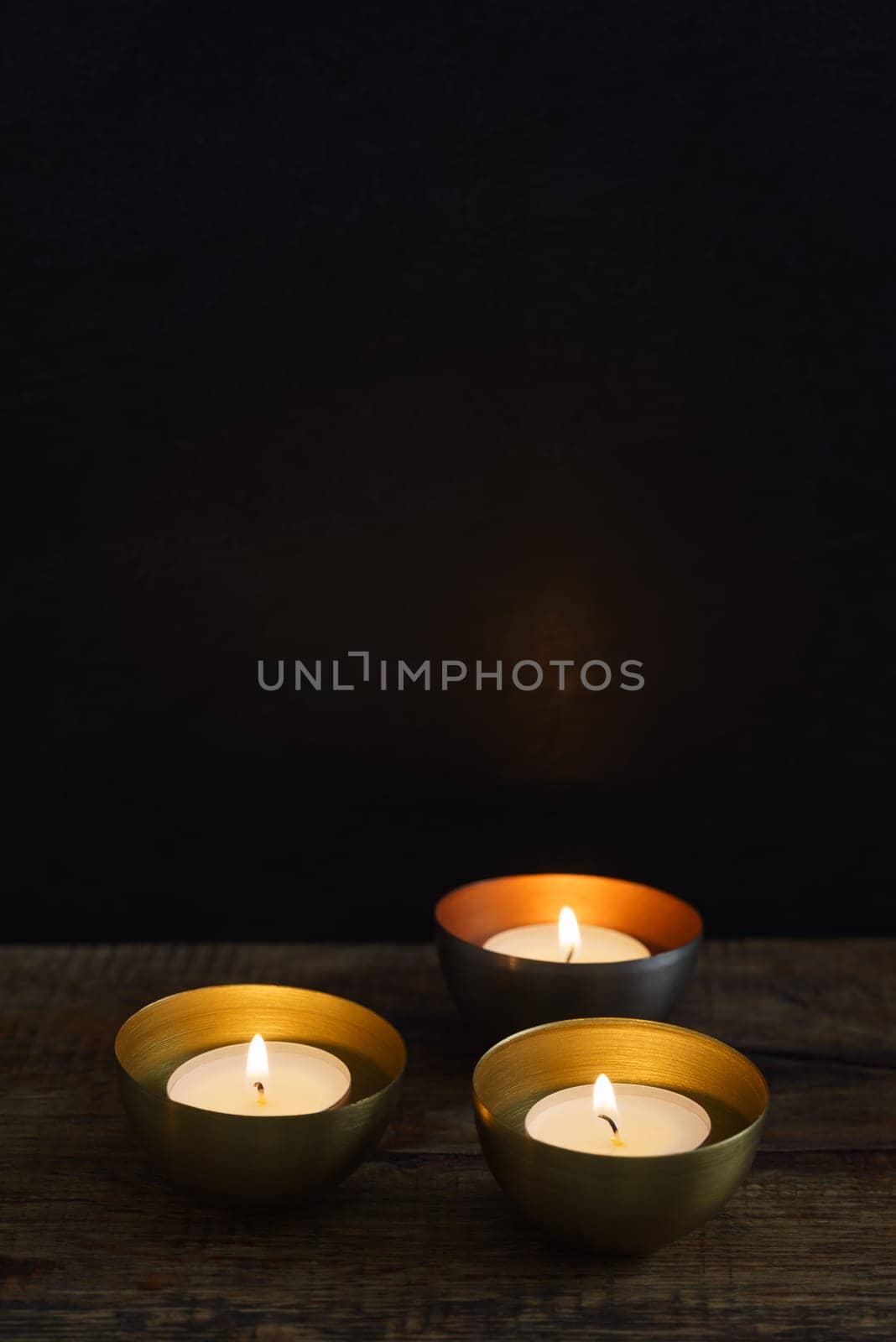 Three votive candles in copper or golden votive candle holders