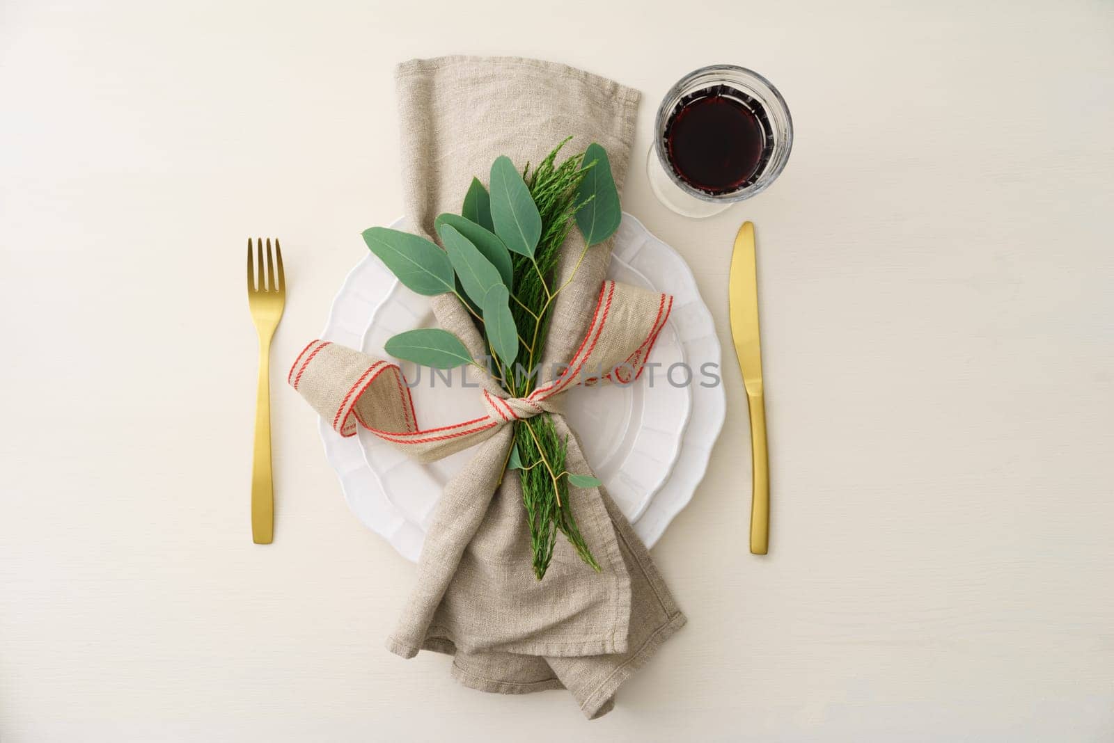 Natural Christmas place setting with golden silverware, eucalyptus and greens