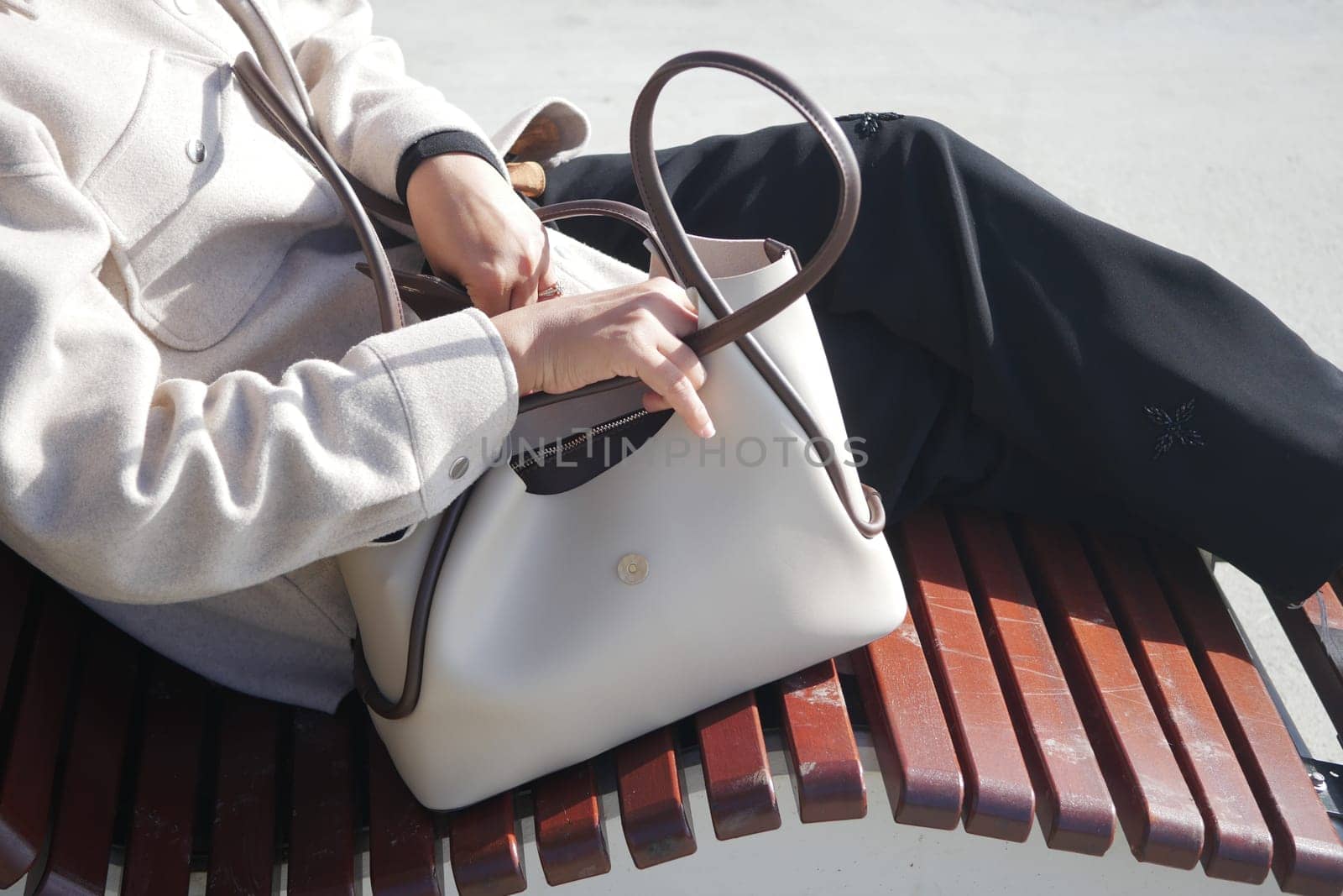 A person enjoys a sunny day while sitting on a wooden bench.