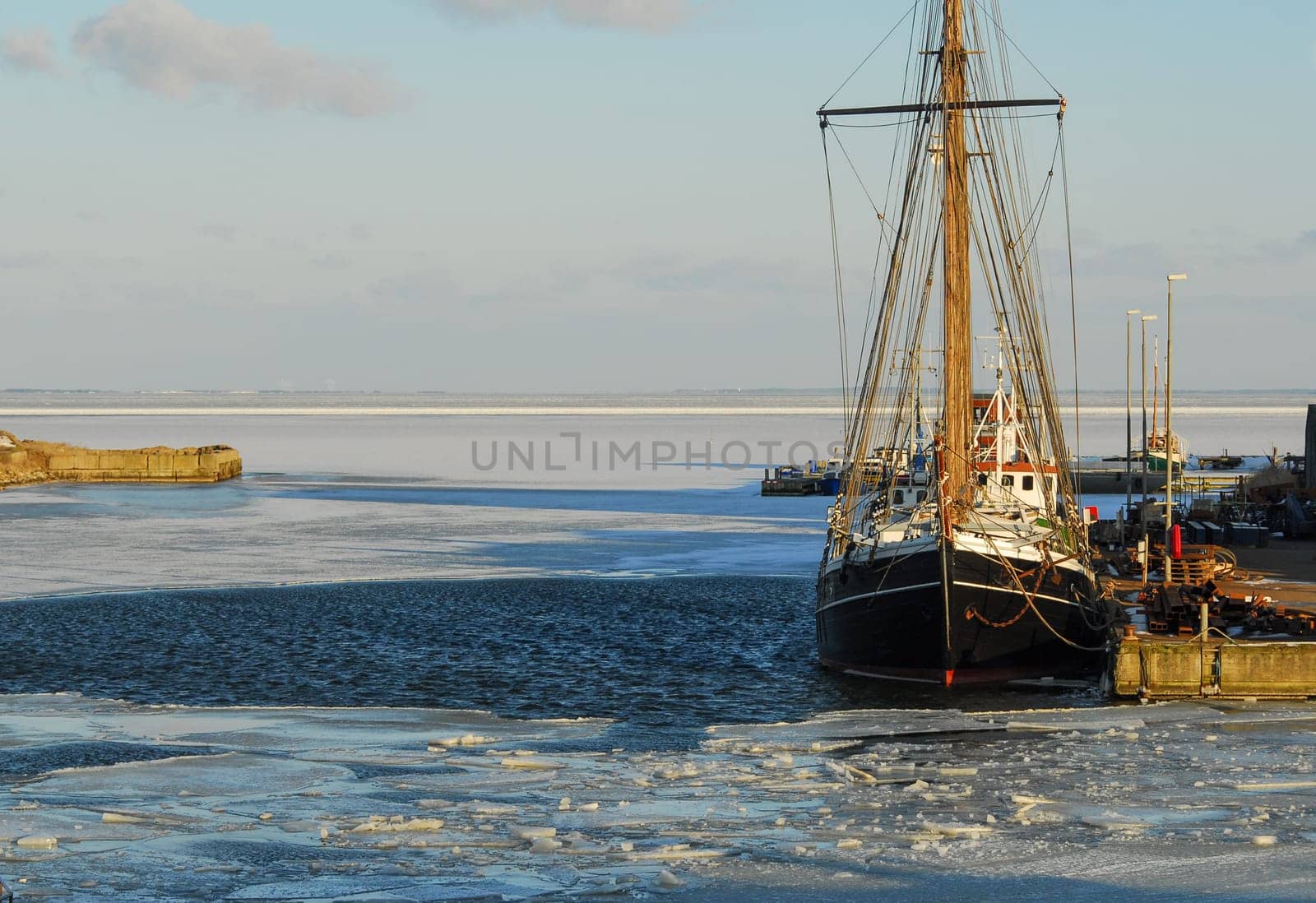 Black fishing boat is docked, while the waves shower. fishing trawler