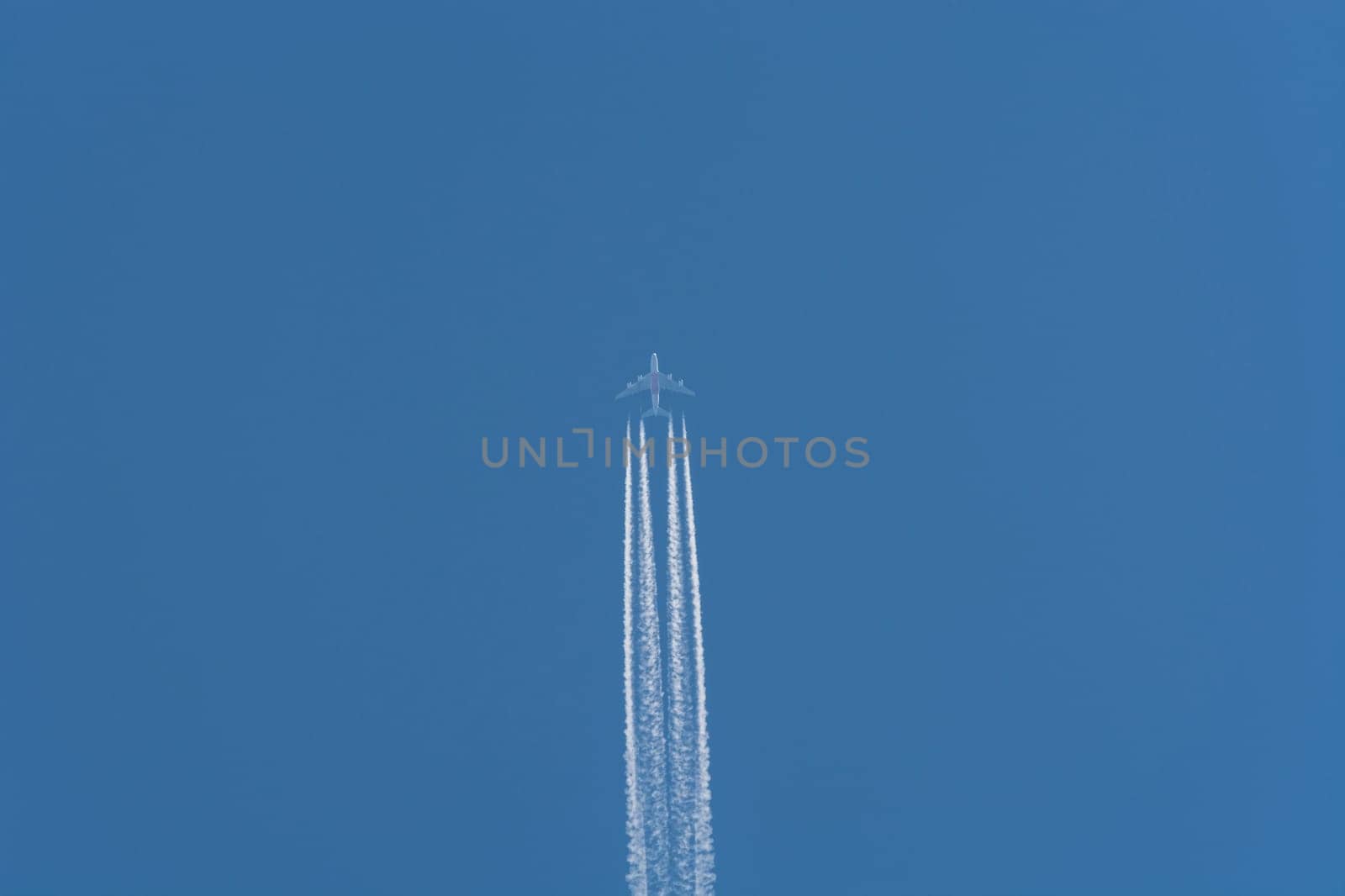 Airplane flying at high altitude contrails against a dark blue sky...