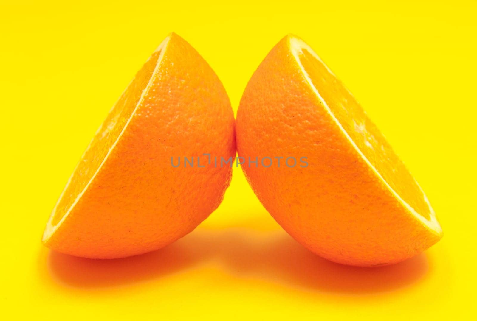 Fresh half orange citrus fruit on yellow background