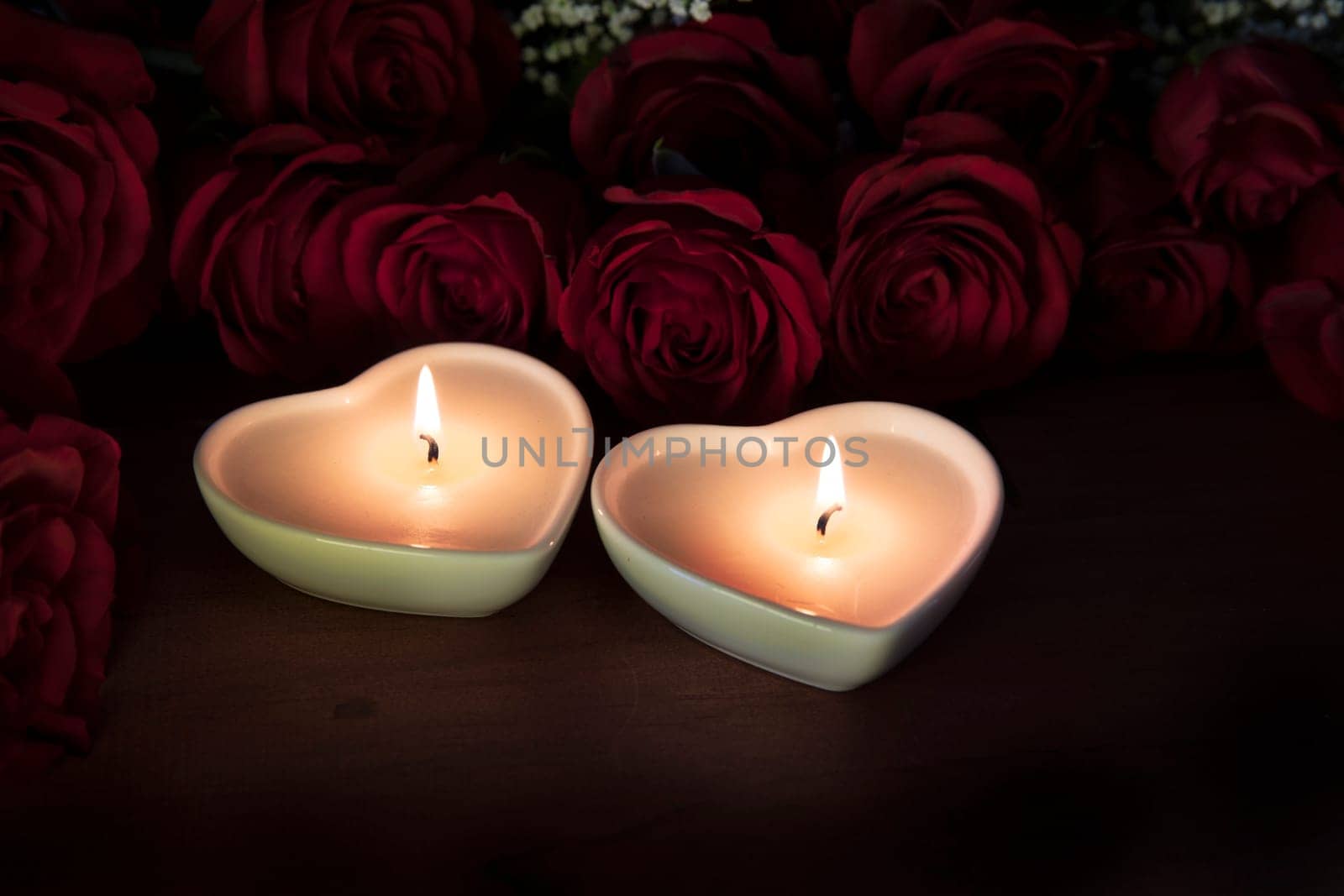 Two heart shaped candles with red roses.
