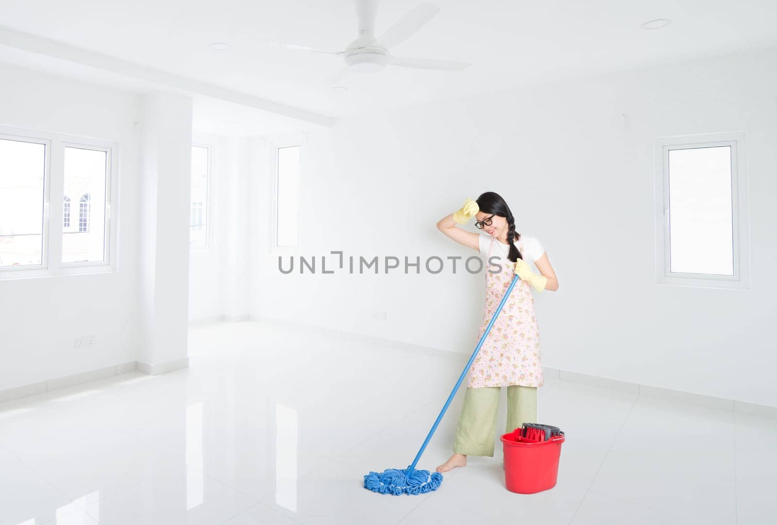Young Asian woman mopping floor with water, cleaning house.