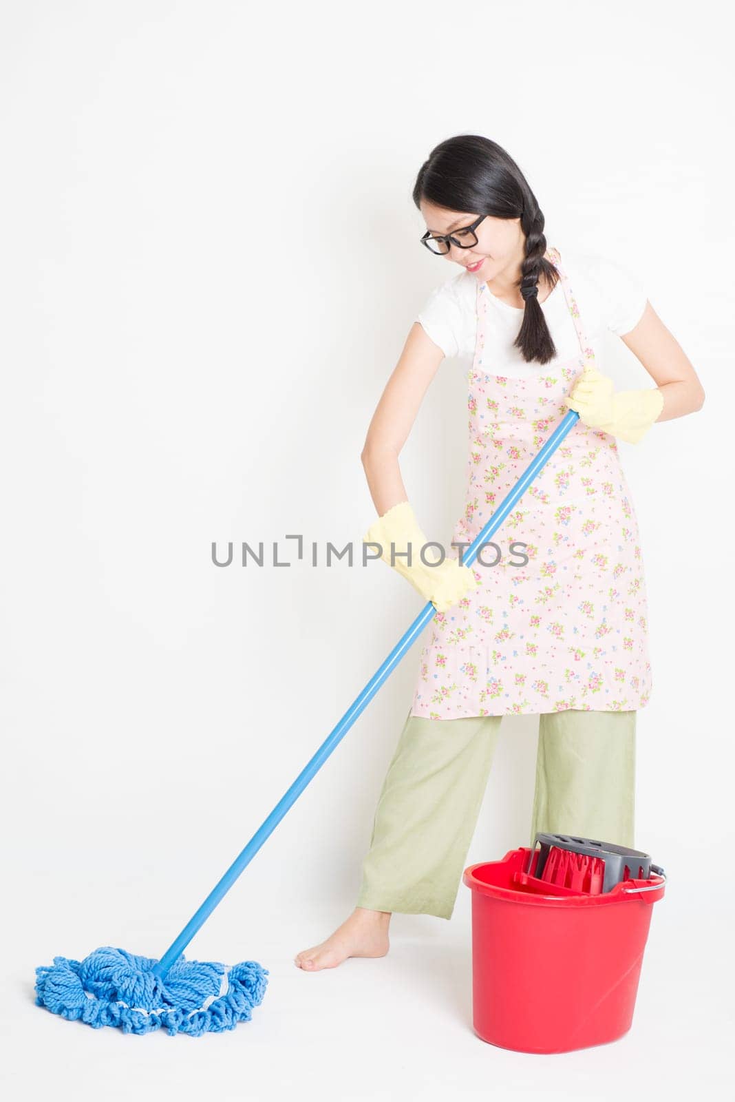 Young Asian housewife mopping floor with water, home cleaning.