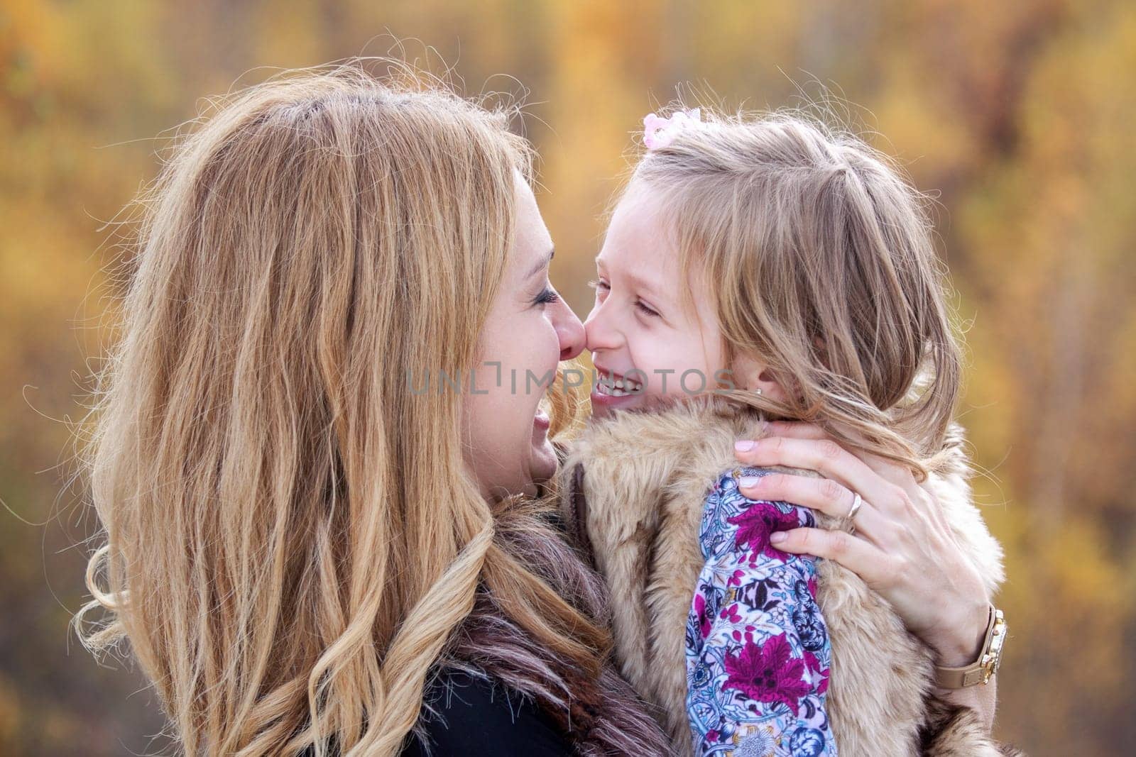 Mother and daughter playing nose to nose in autumn nature