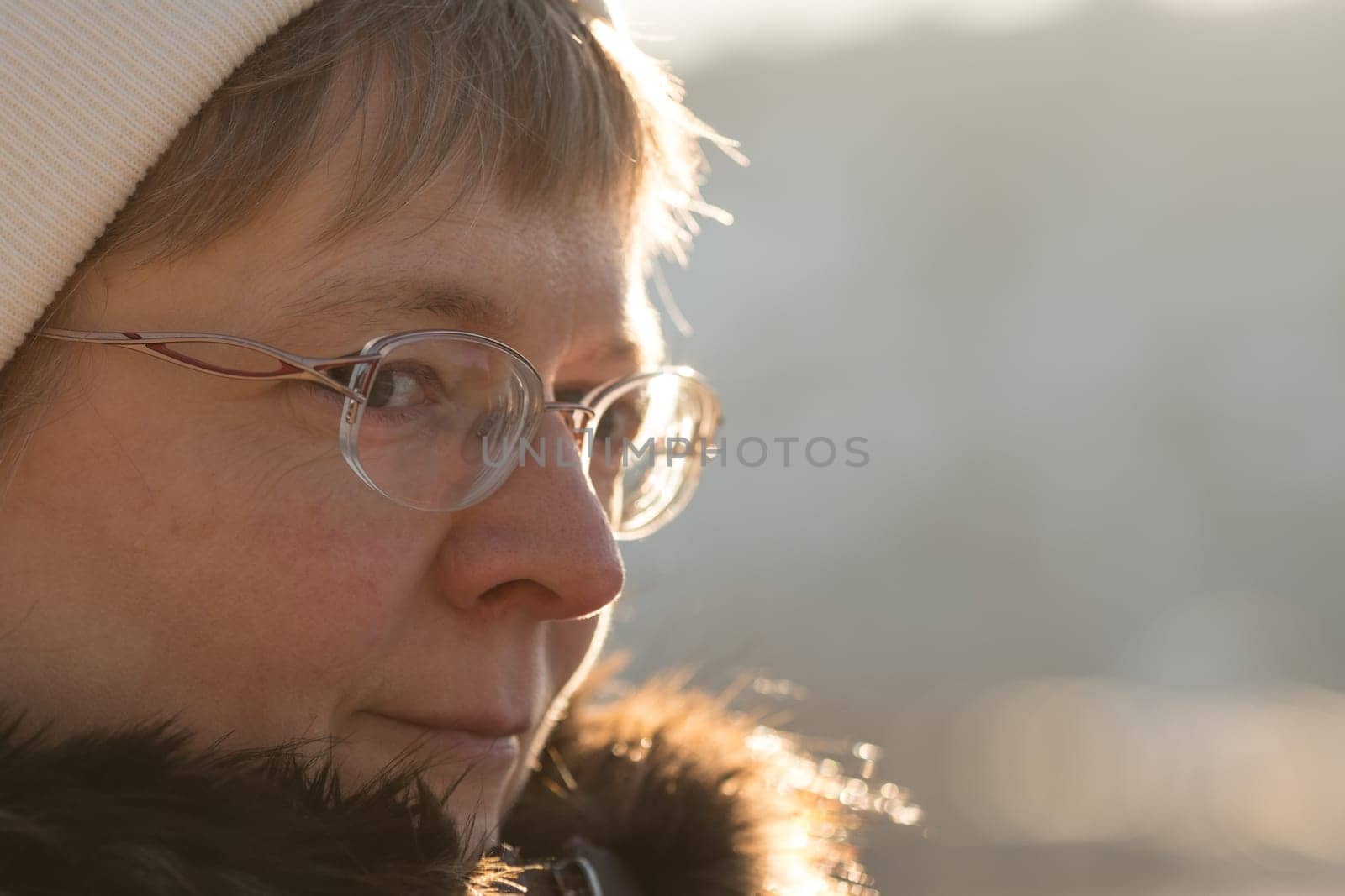Cheerful looking blonde woman with glasses in the backlight