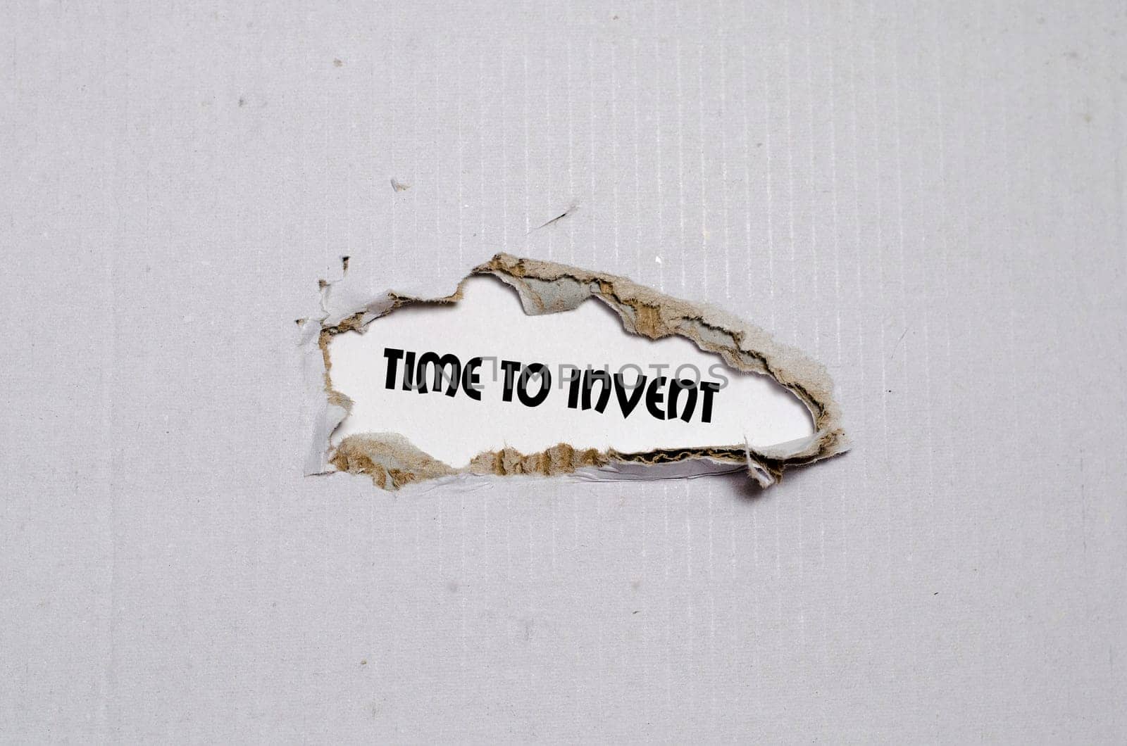 The word time to invent appearing behind torn paper