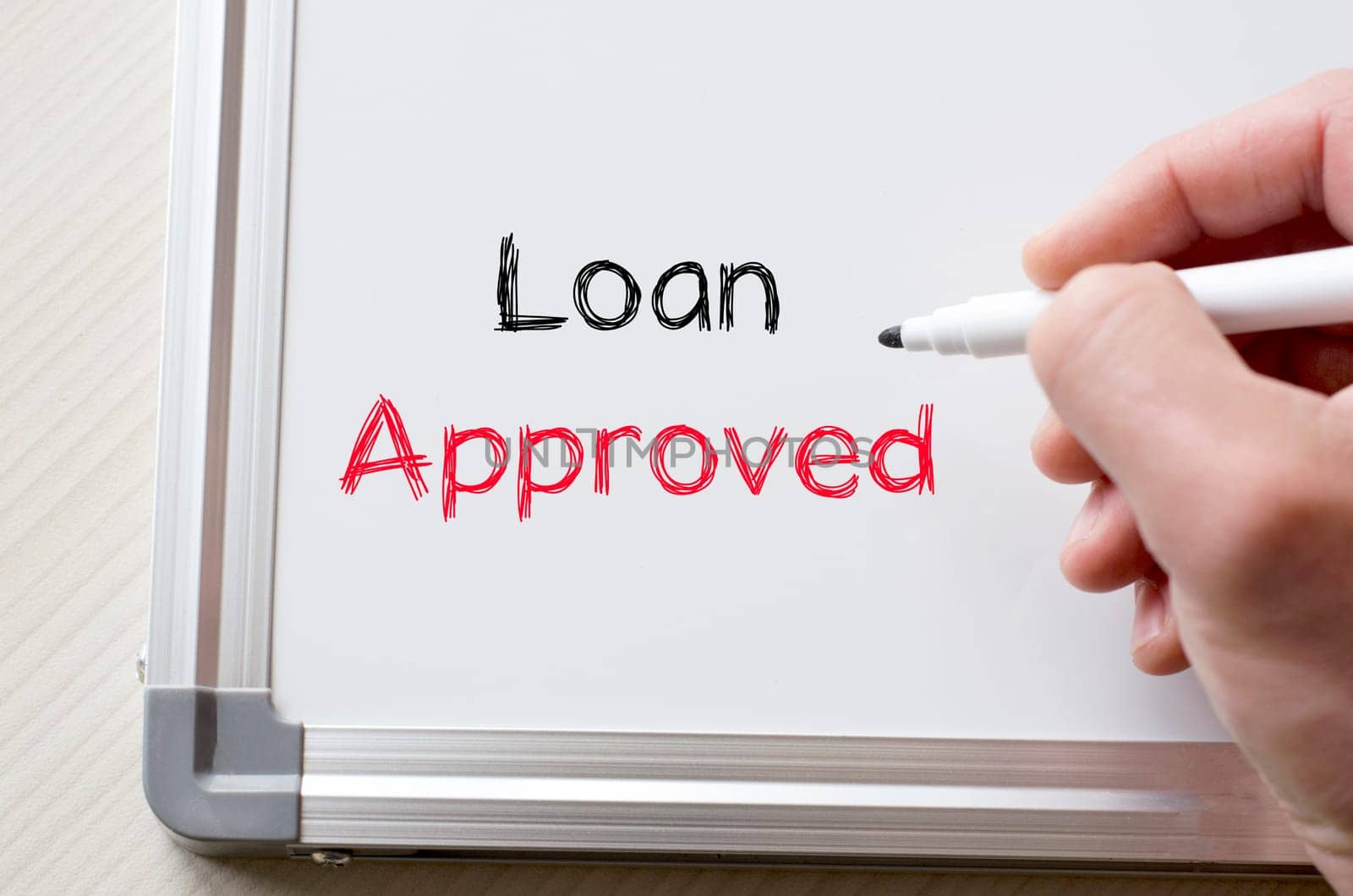 Human hand writing loan approved on whiteboard