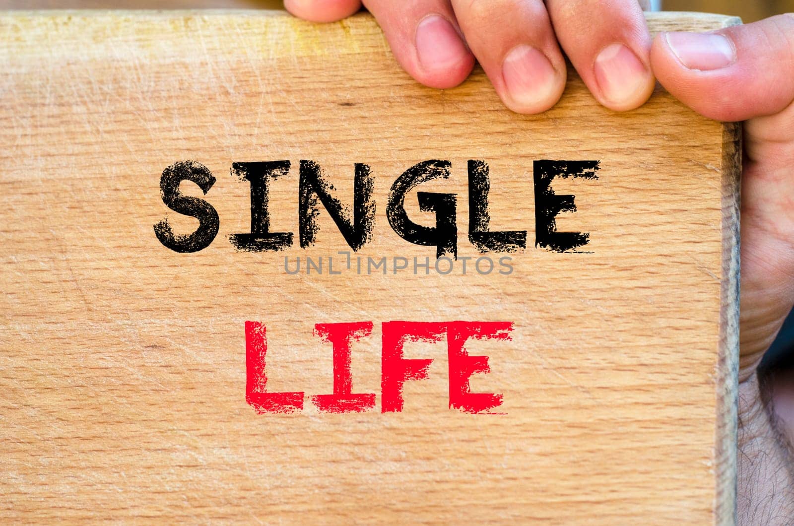 Human hand over wooden background and single life text concept