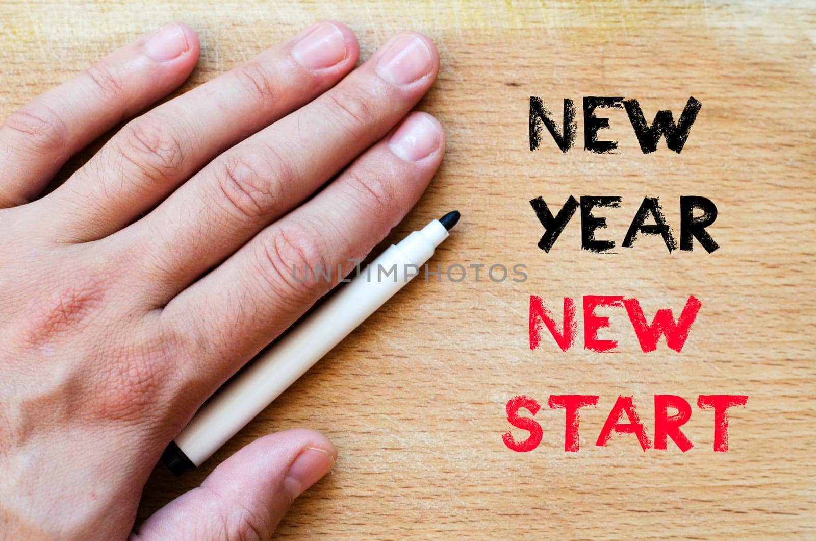 Human hand over wooden background and new year new start text concept