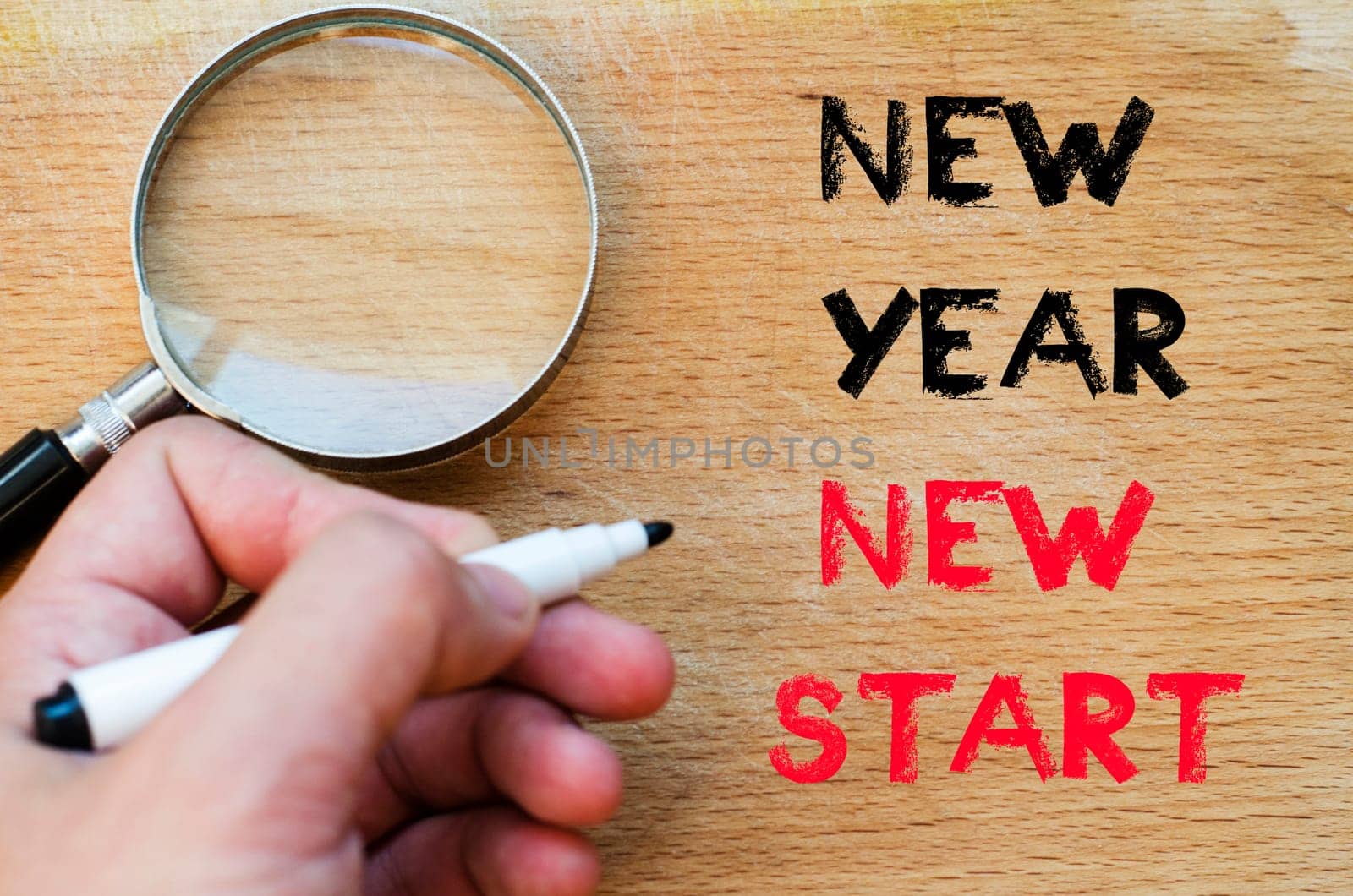 Human hand over wooden background and new year new start text concept