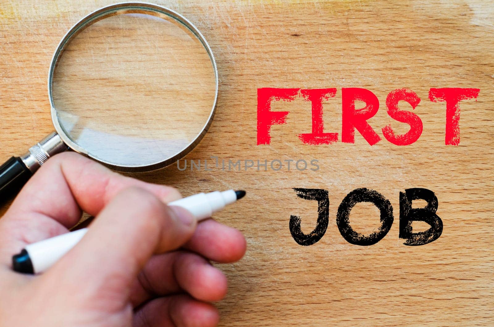 Human hand over wooden background and first job text concept