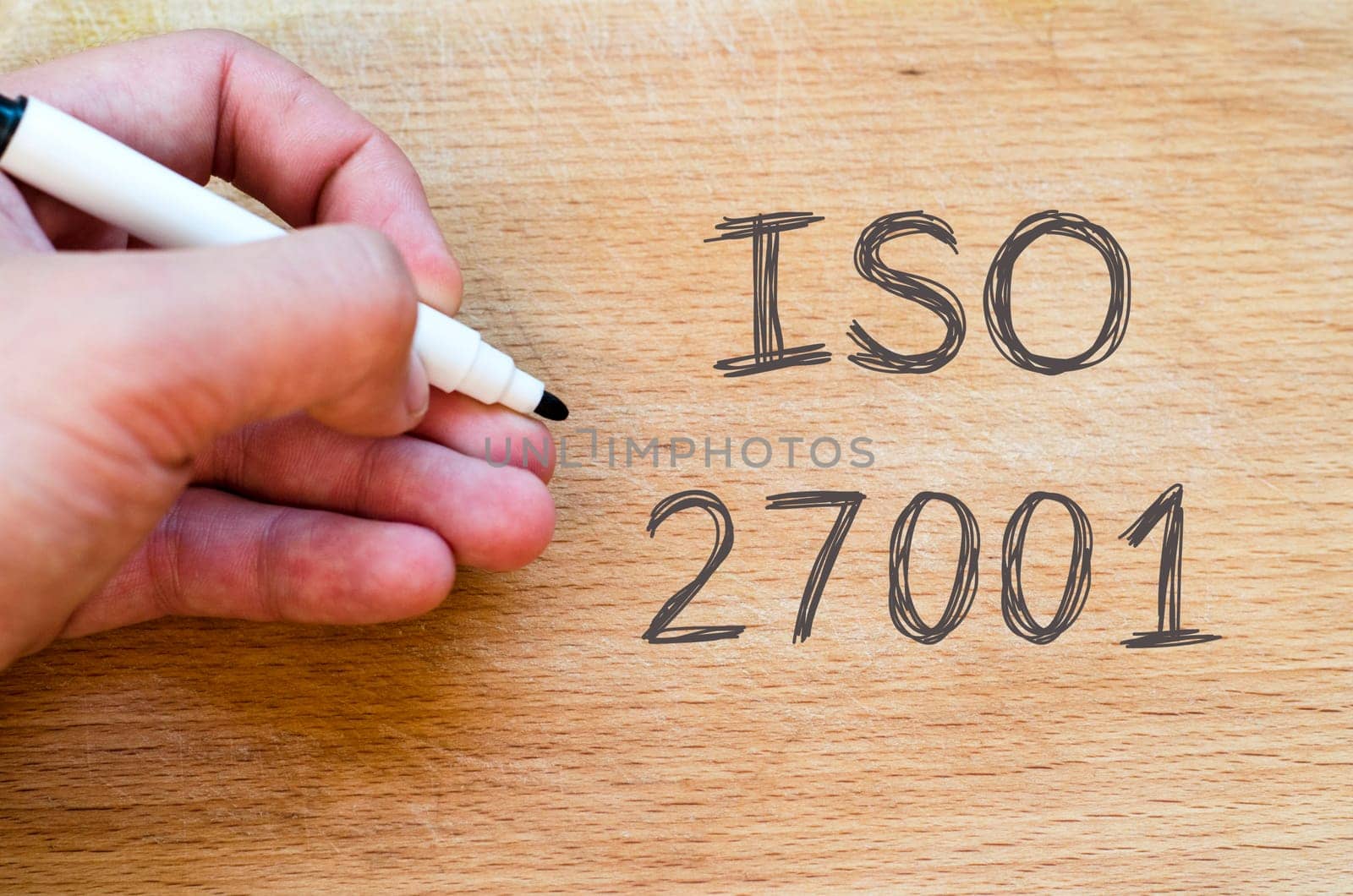 Human hand over wooden background and iso 27001 text concept