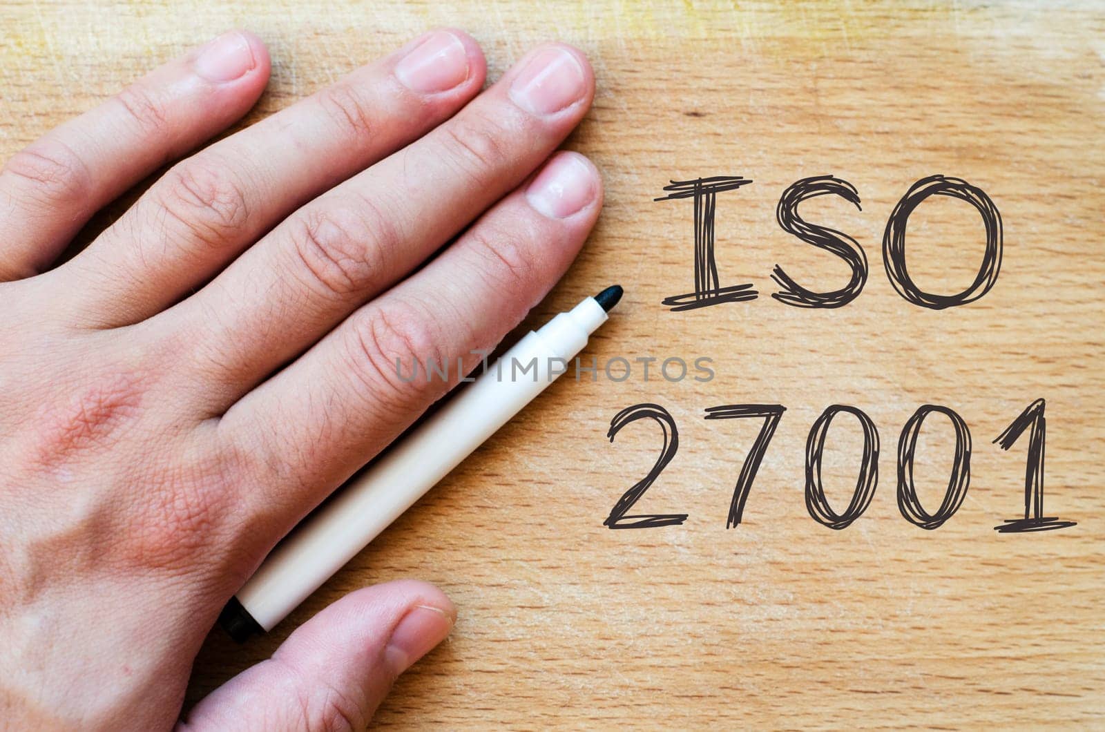Human hand over wooden background and iso 27001 text concept