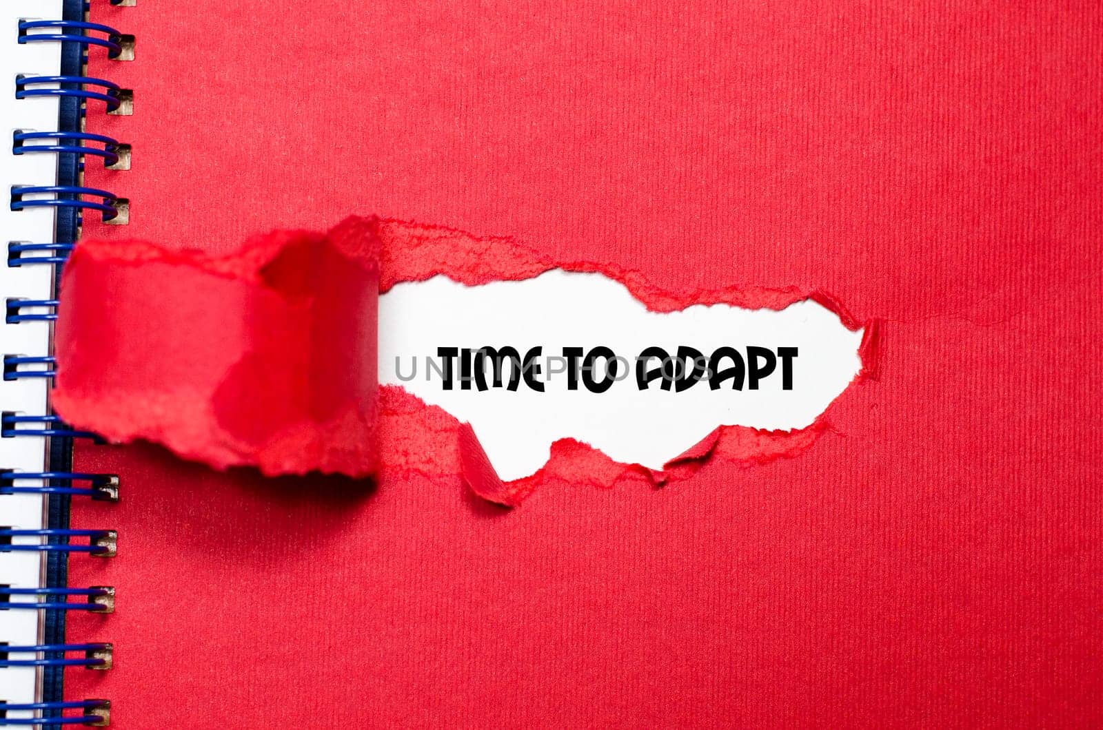 The word time to adapt appearing behind torn paper