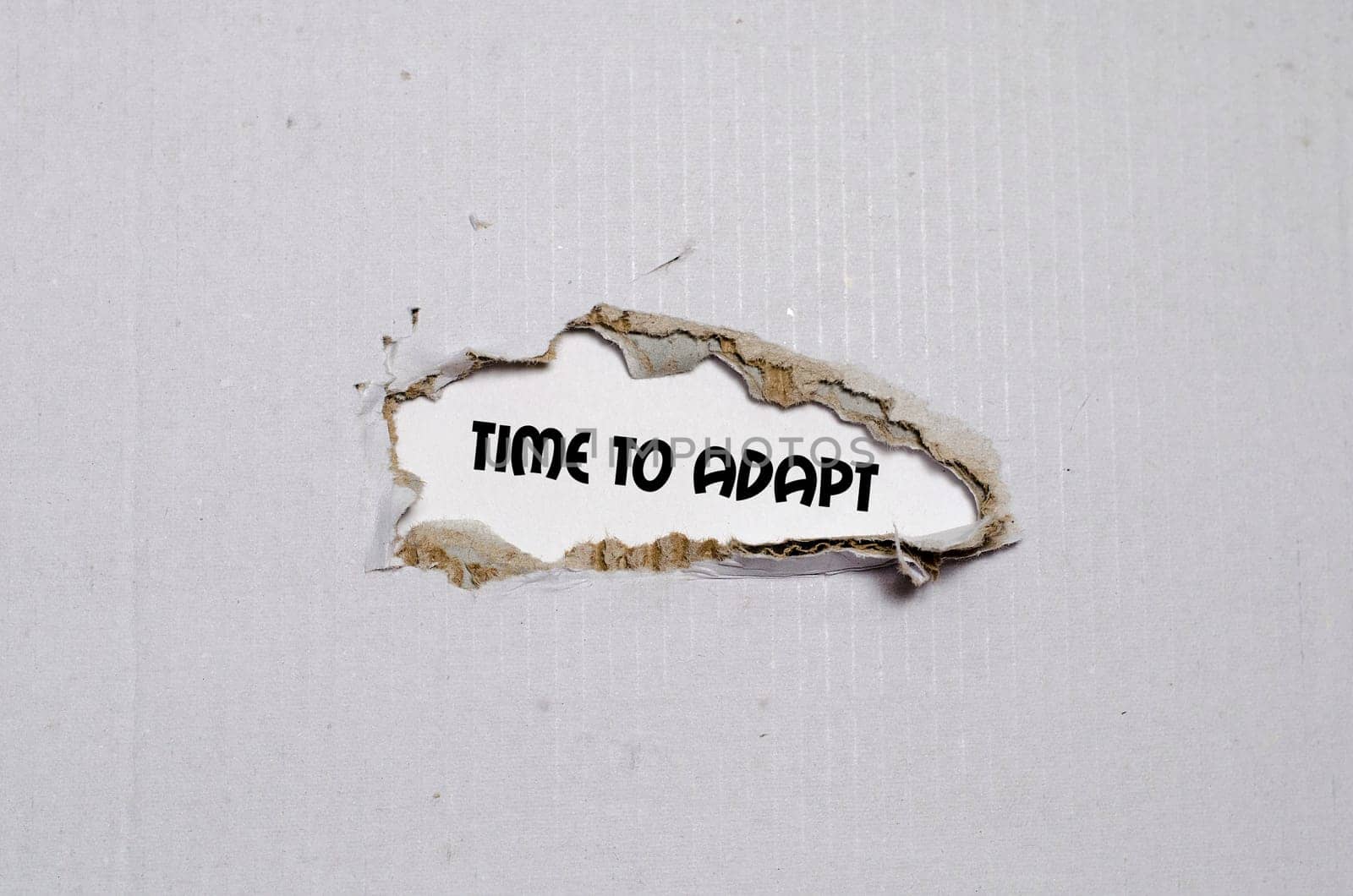 The word time to adapt appearing behind torn paper