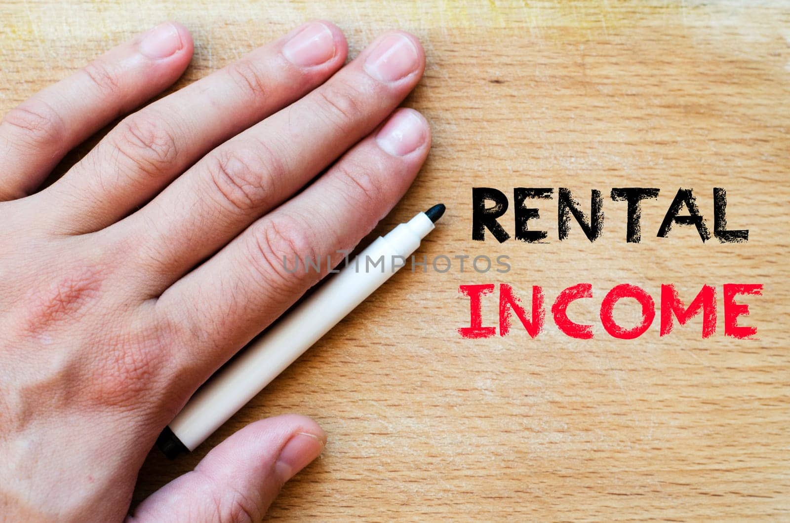 Human hand over wooden background and rental income text concept