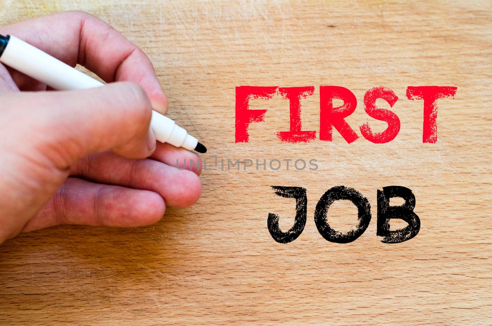 Human hand over wooden background and first job text concept