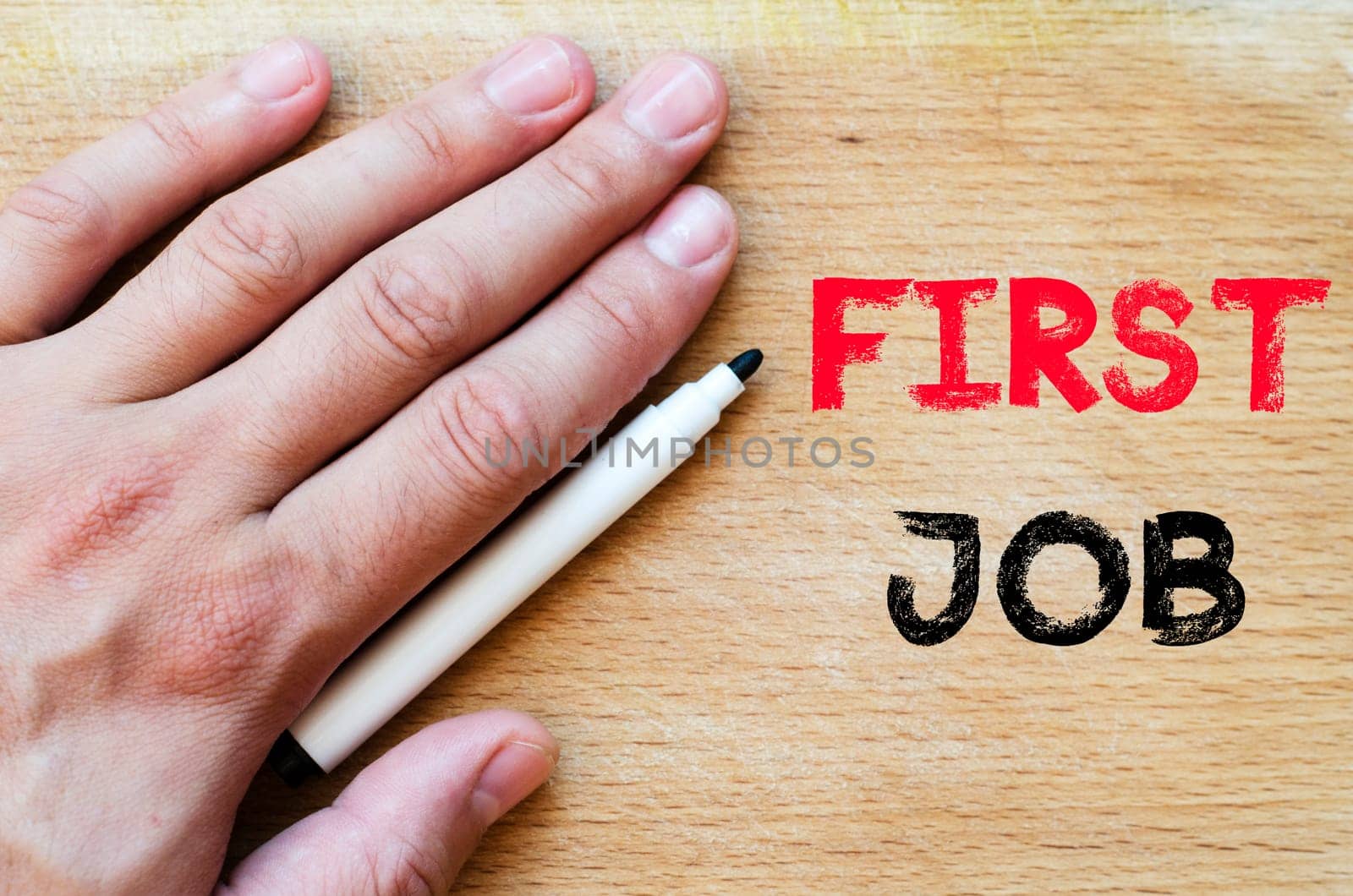 Human hand over wooden background and first job text concept