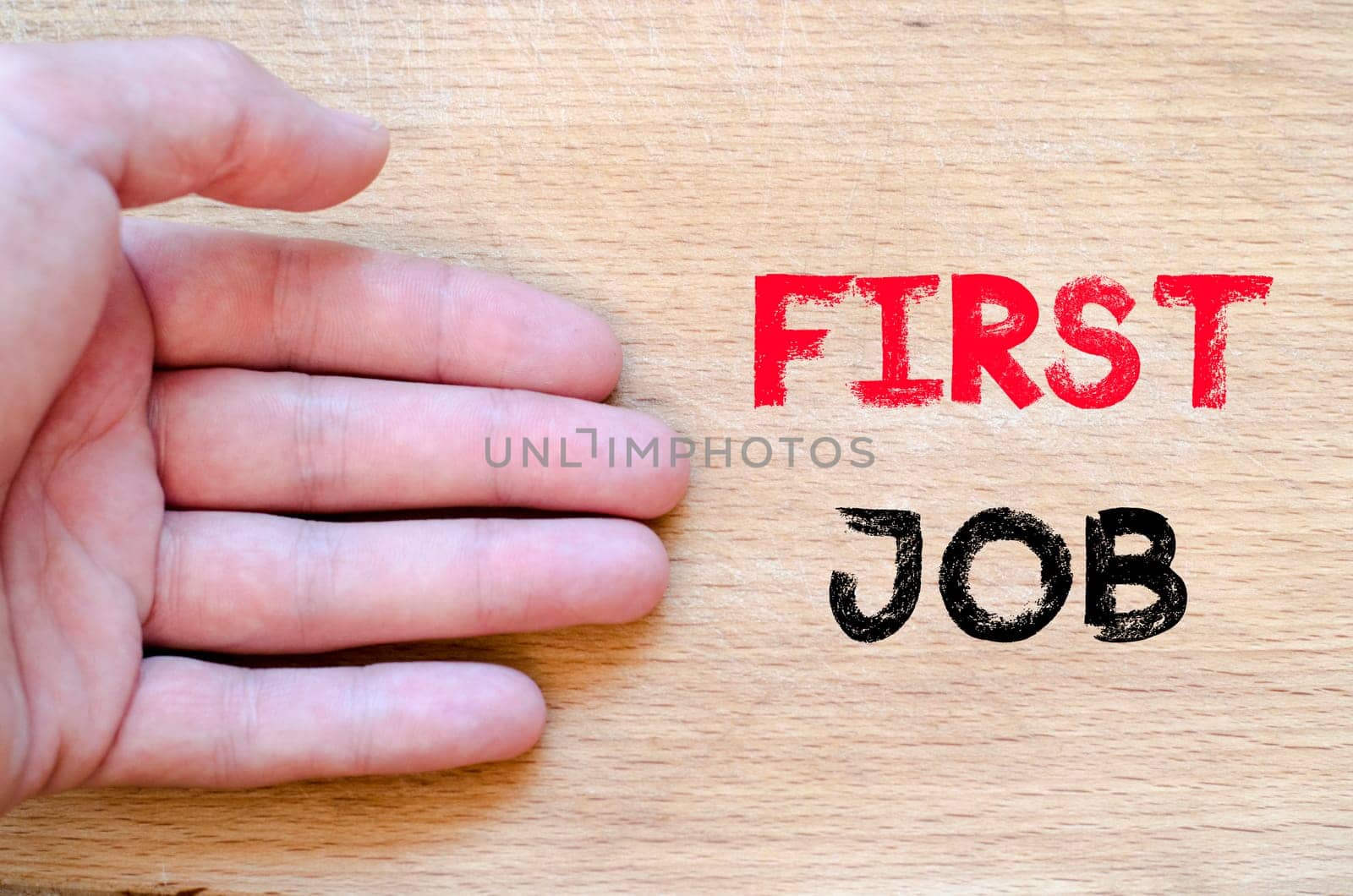 Human hand over wooden background and first job text concept