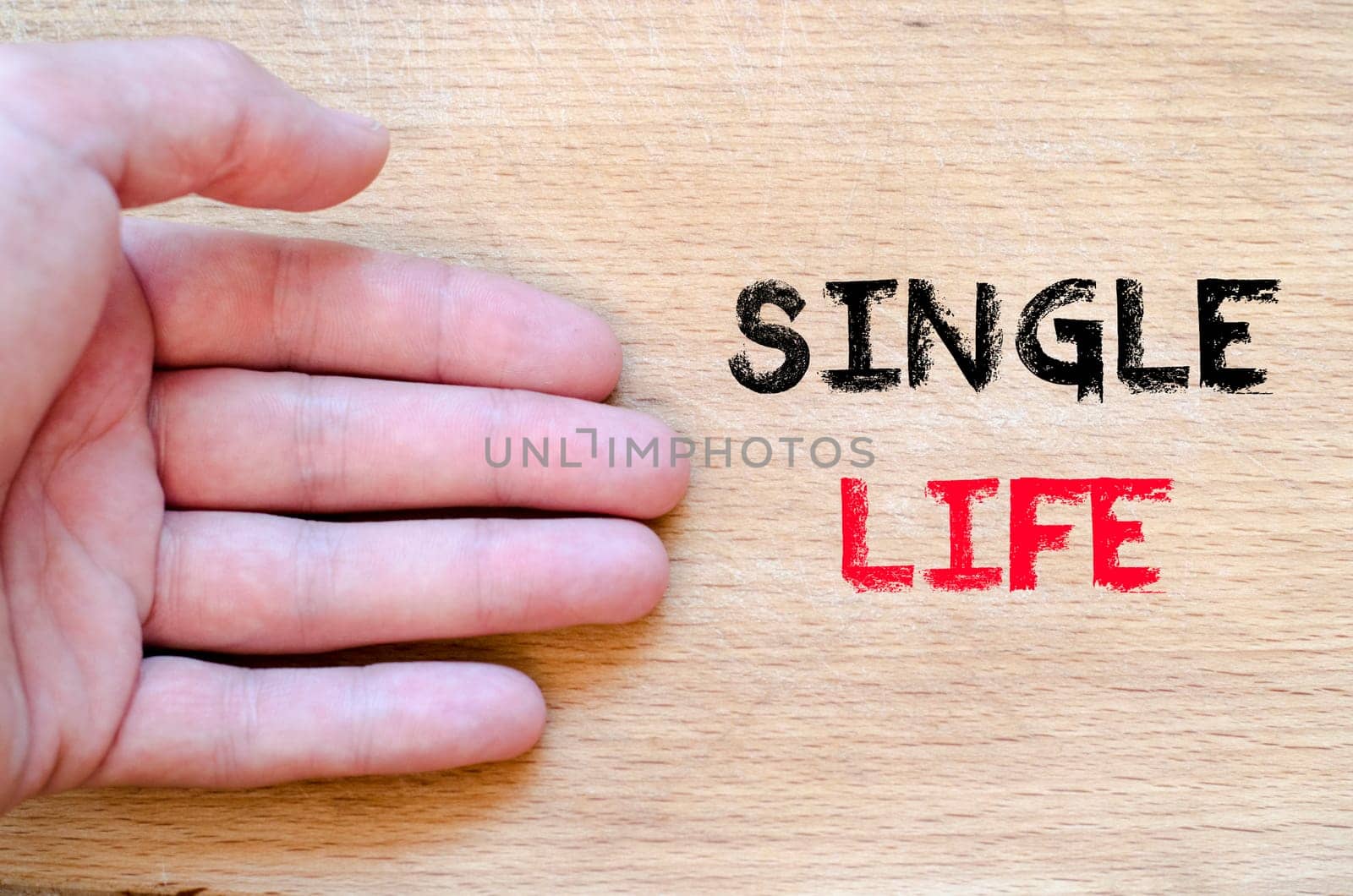 Human hand over wooden background and single life text concept