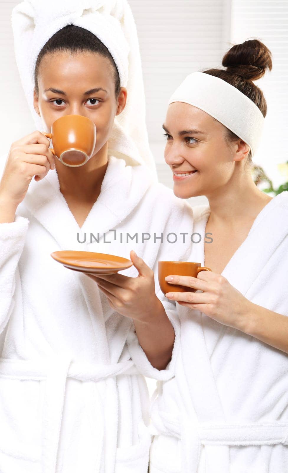 relax in the beauty salon,coffee with a friend. coffee,relaxation and beauty women in a beauty salon. two women in living room wellness dressed in white robes with cups of coffee