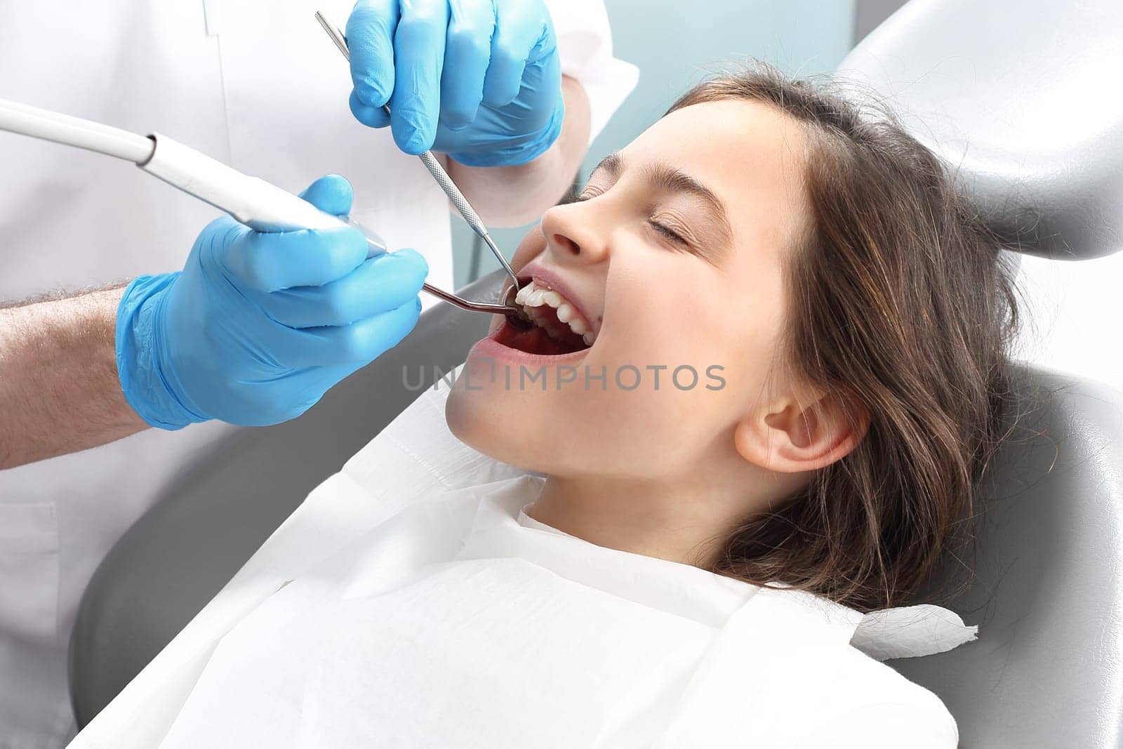 a child in a dental chair during a dental treatment. treatment of tooth loss,a child at the dentist. a dental office,a child in a dental chair. tooth treatment,the dentist cleans the cavity