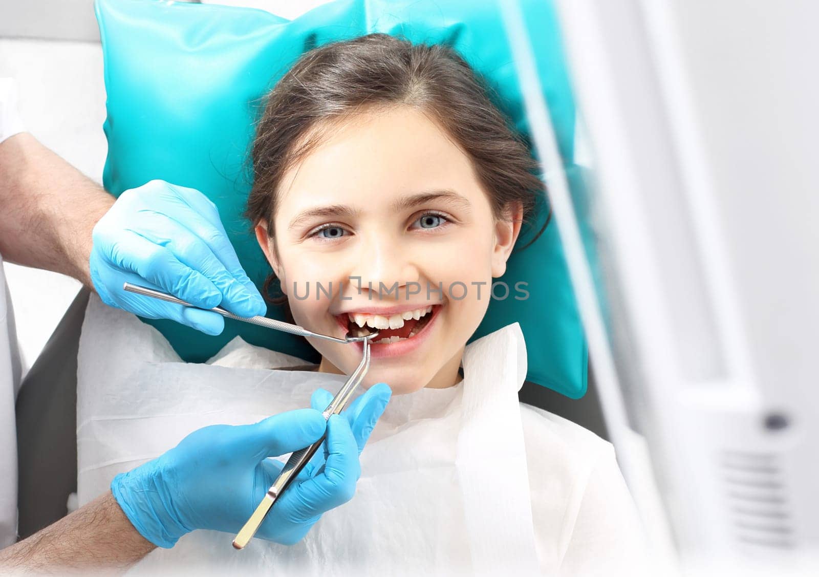 a child in a dental chair during a dental treatment. treatment of tooth loss,a child at the dentist. a dental office,a child in a dental chair. tooth treatment,the dentist cleans the cavity