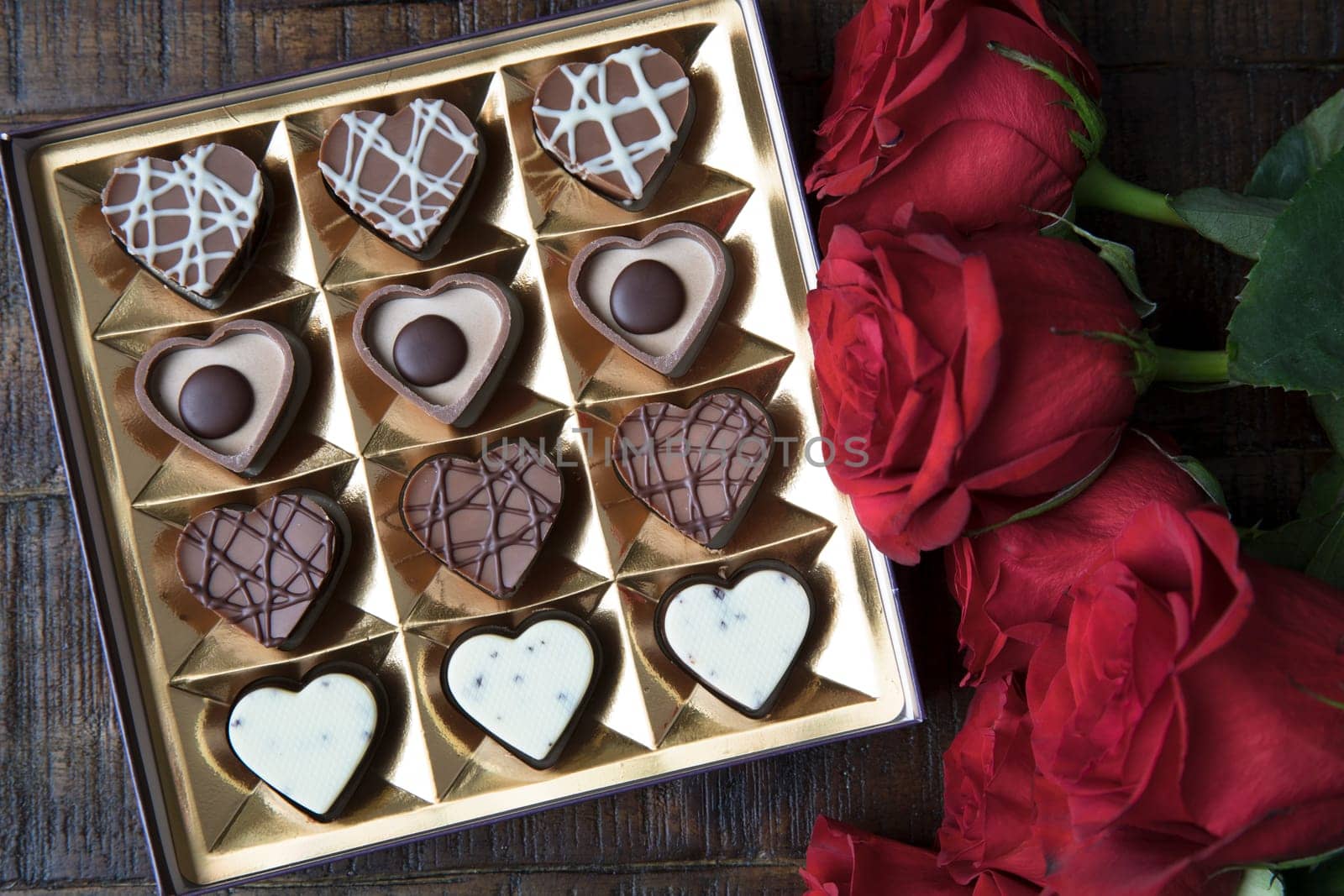 Box of romantic heart shaped chocolates and red roses.