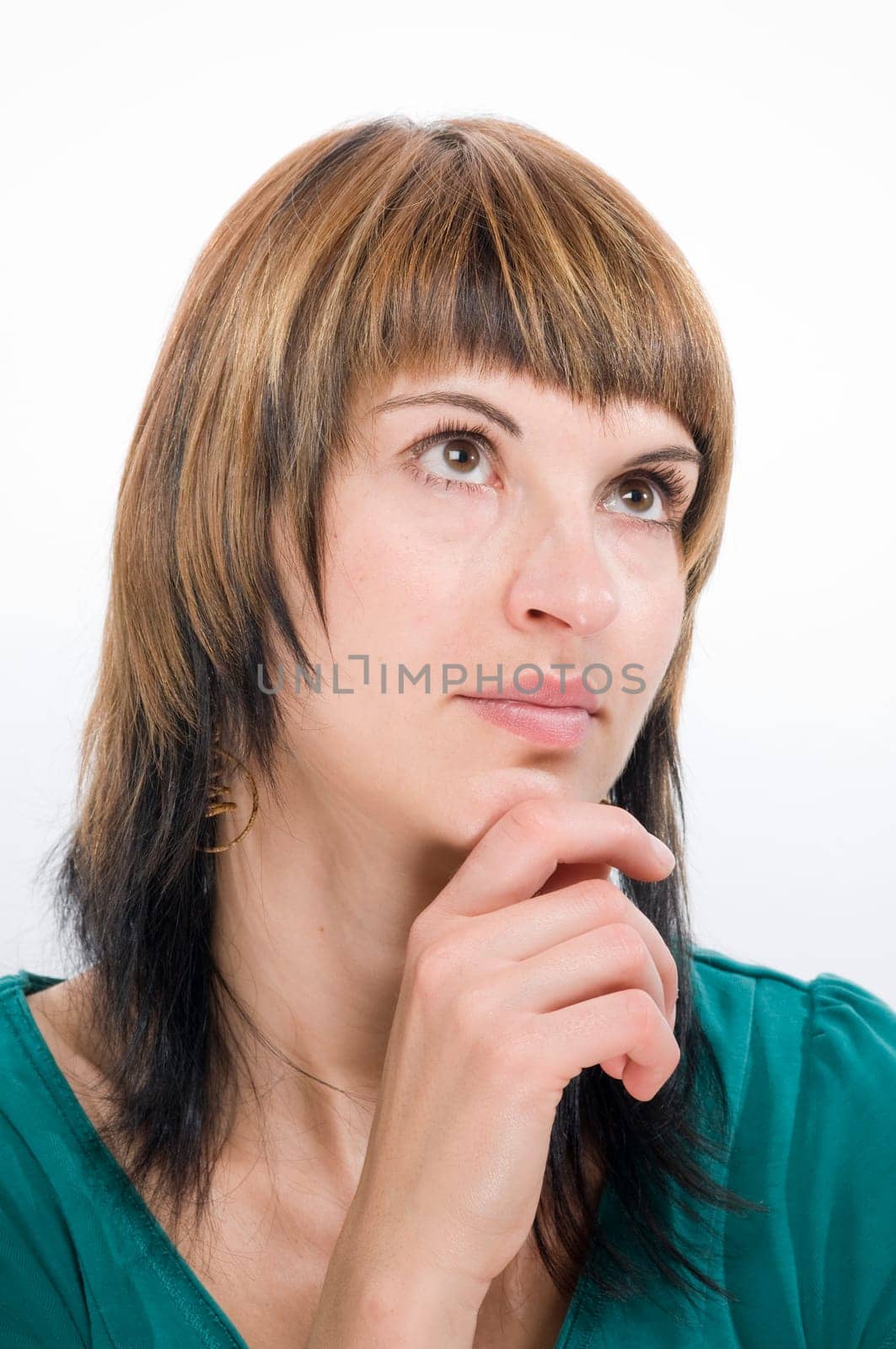 Head portrait of a young brunette woman against a white background looking thoughtfully upwards.