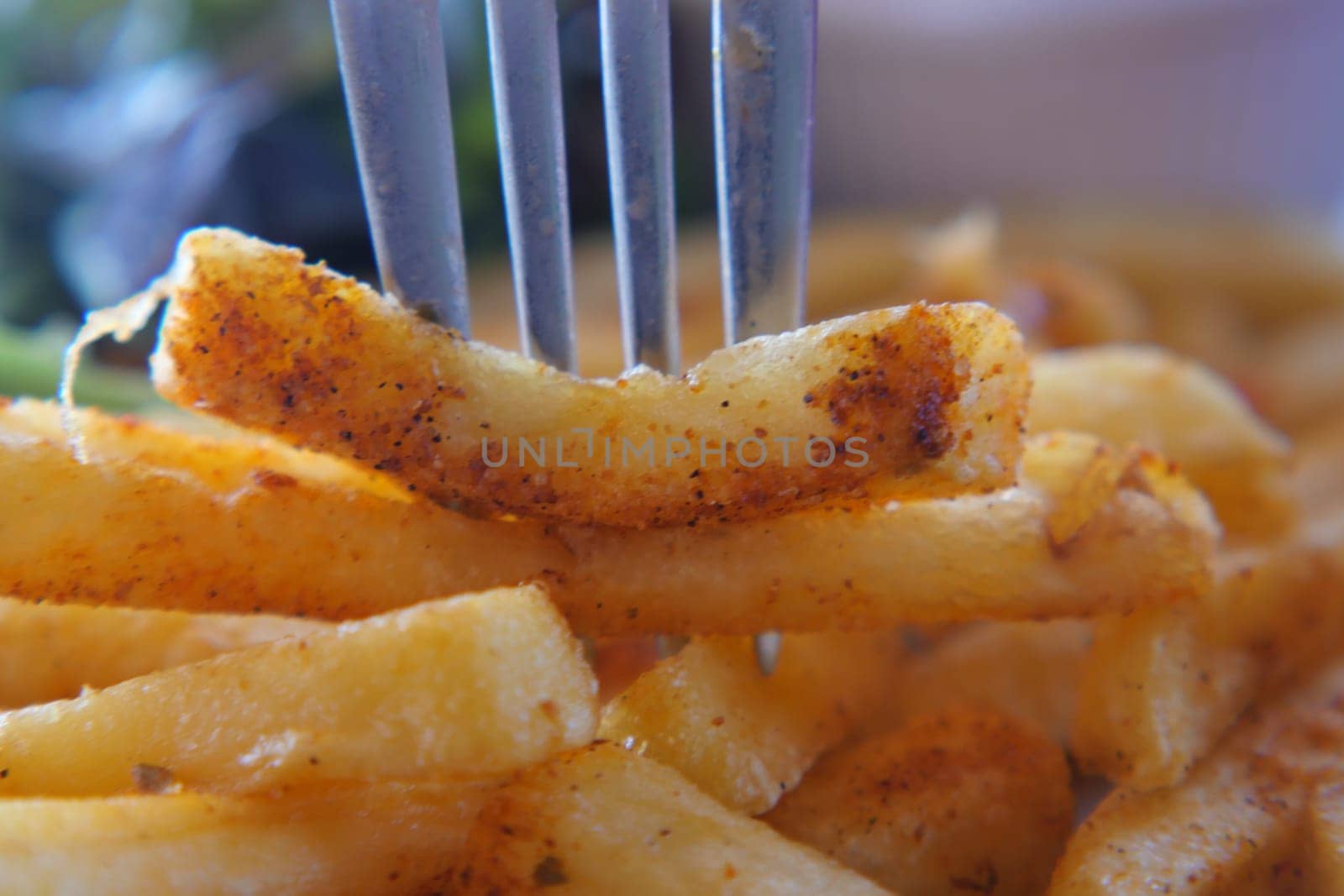 A fork holds a crispy fry, showcasing its seasoned surface and texture.