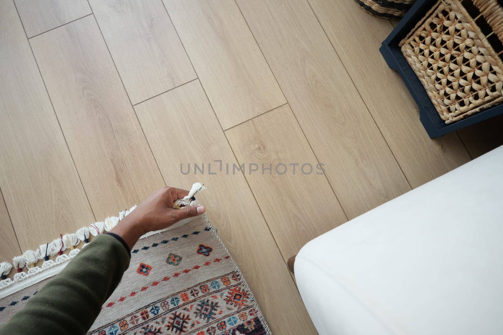 Hand gently pulling on a colorful rug in a stylish living space.