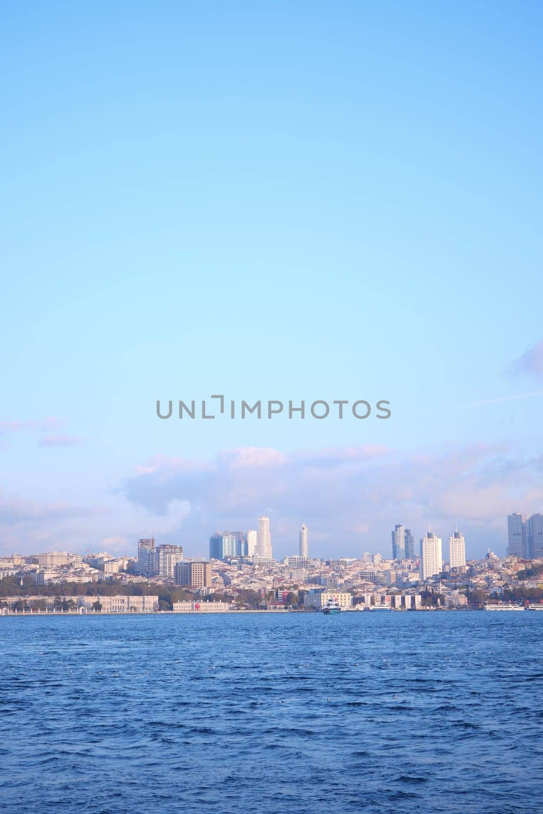 Modern structures rise above the waterfront near the tranquil blue sea.