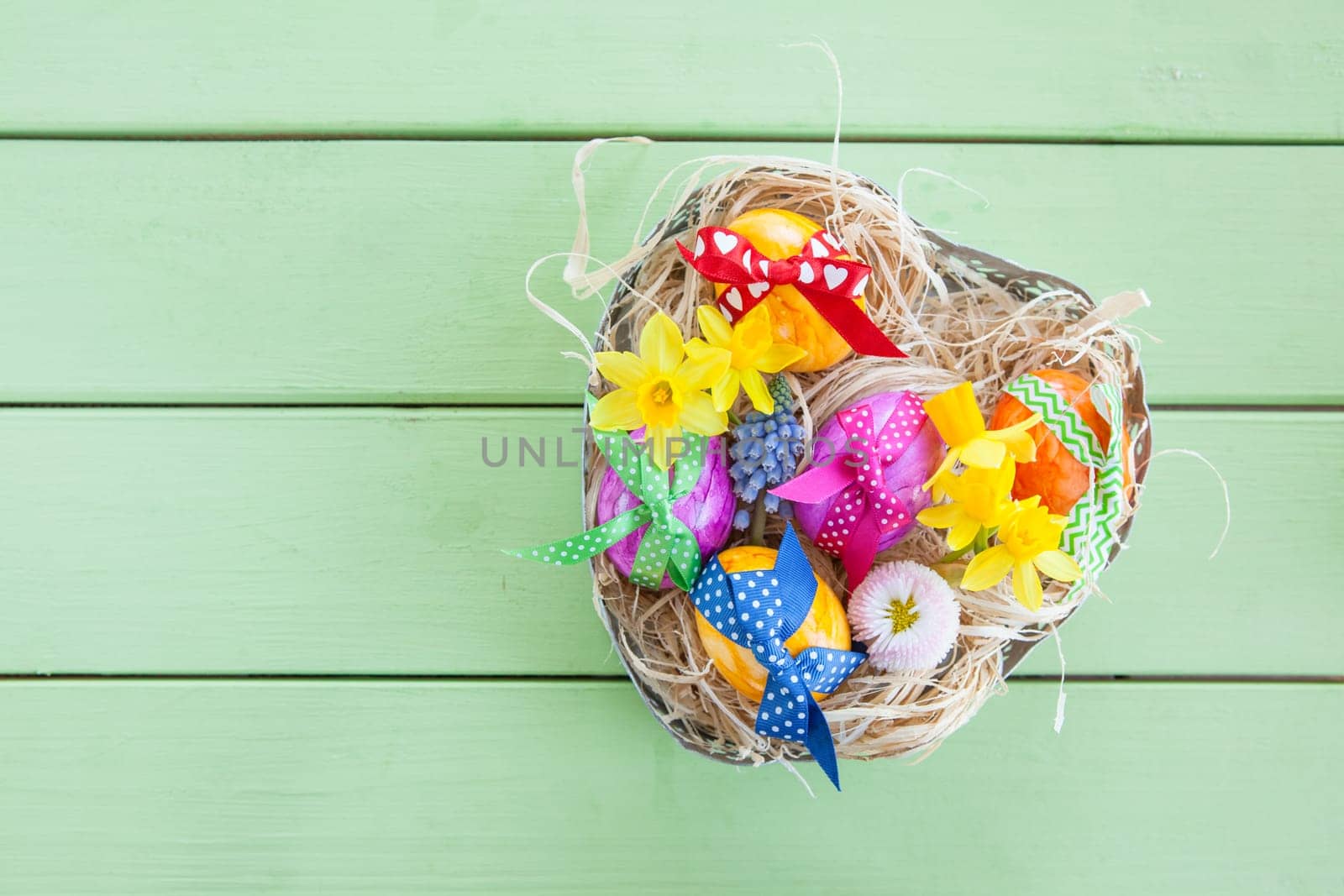 Hearty basket with colourful eggs and flowers for Easter