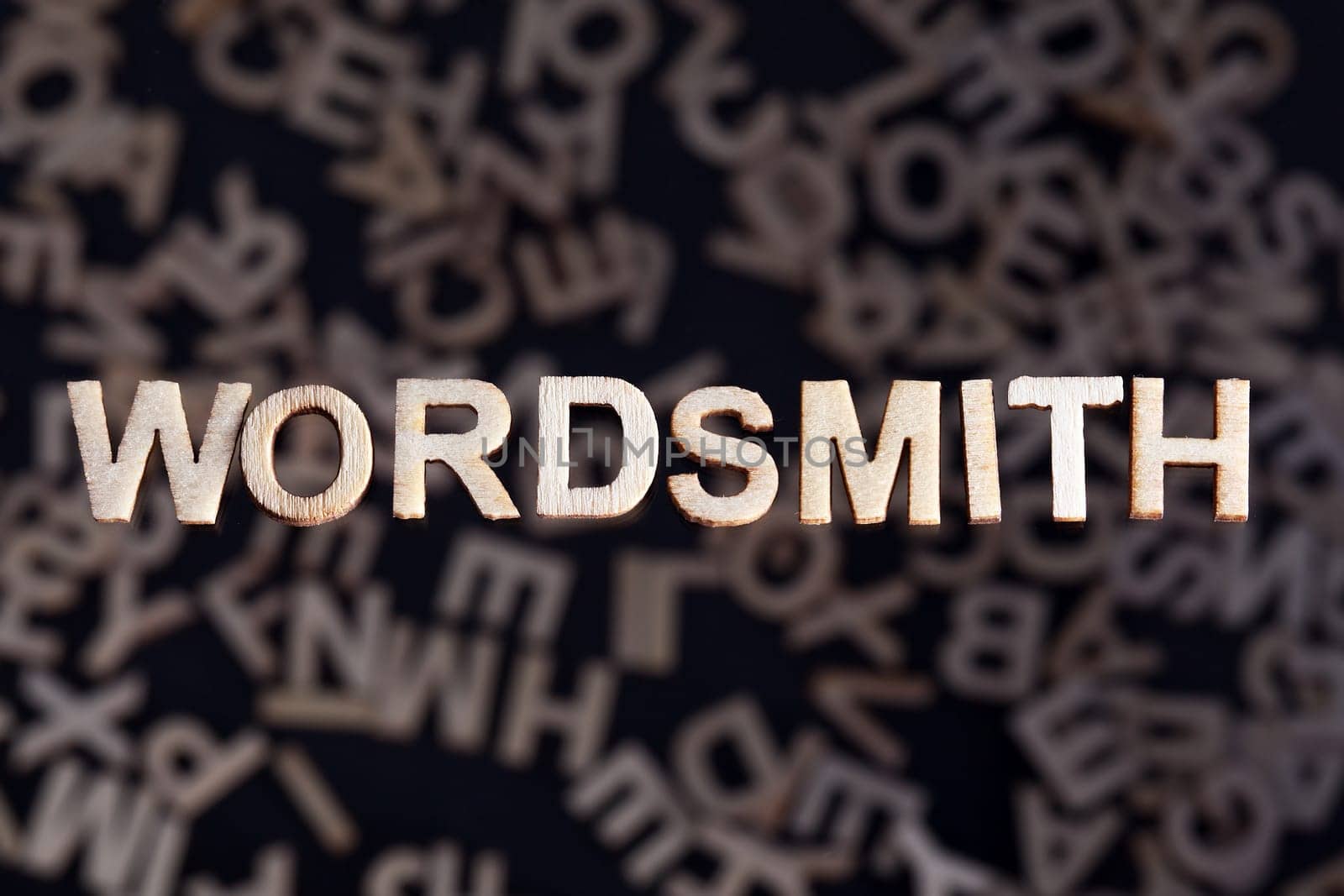 Wordsmith wooden letters created in wood floating above random letters below out of focus on a black background