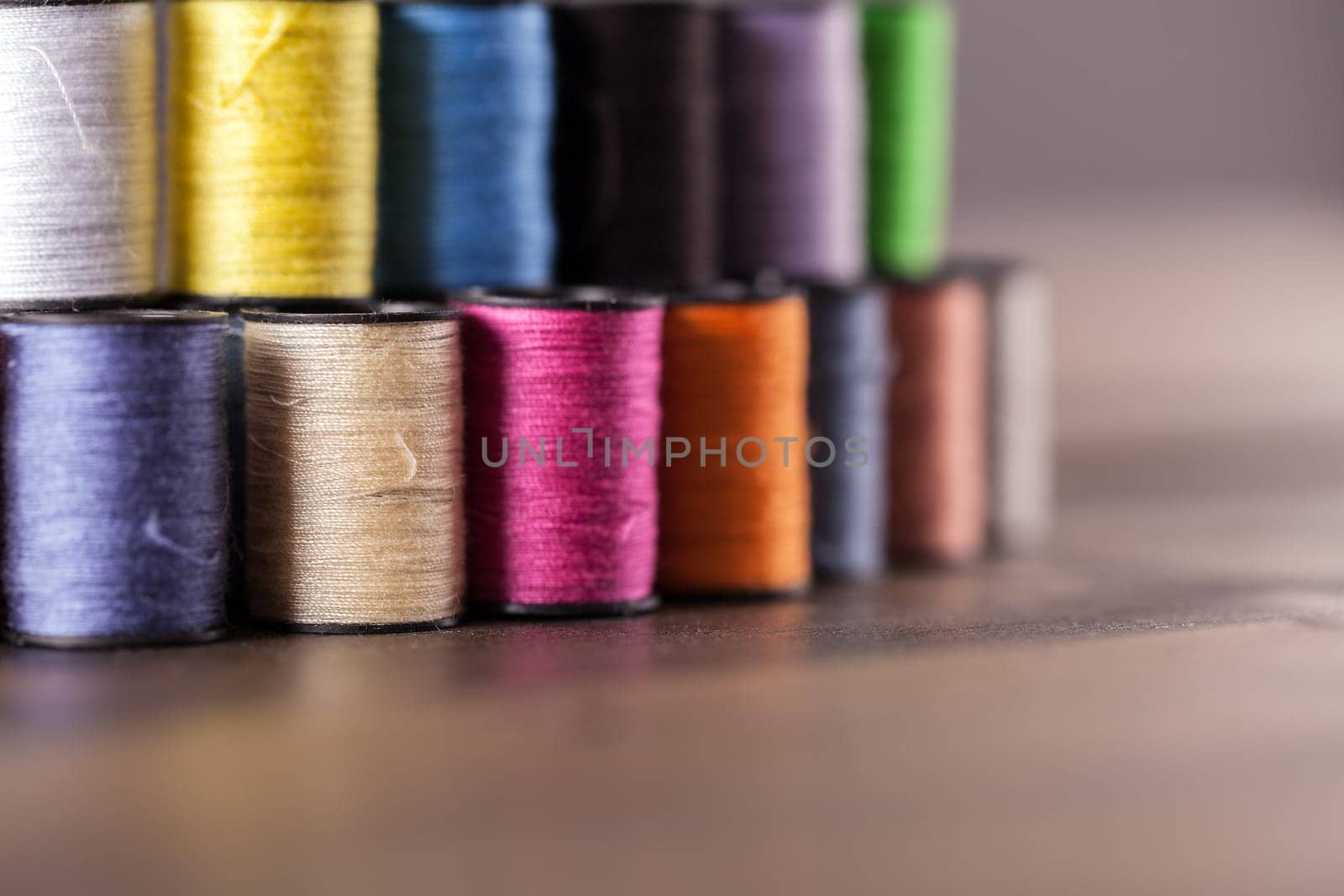 Colorful cotton reels lined and stacked together in a row and viewed at an angle to create shallow depth of field