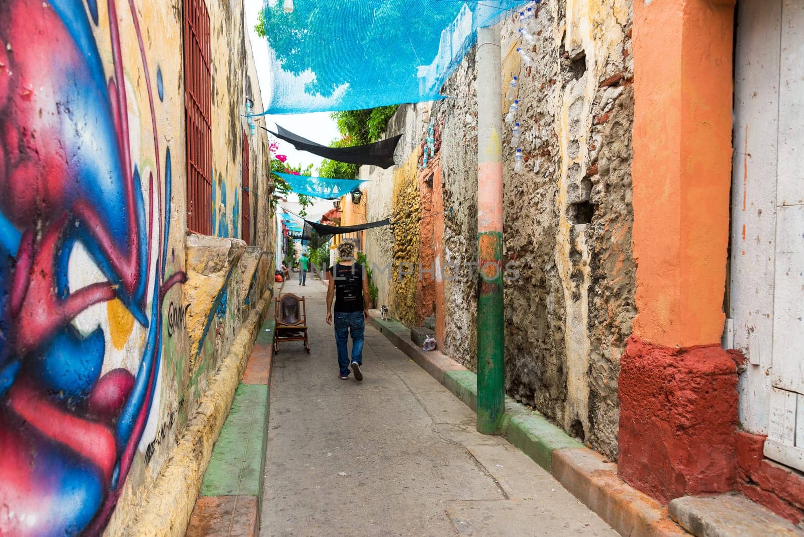 CARTAGENA, COLOMBIA - MAY 24: People walk through a narrow alley in the Getsemani neighborhood in Cartagena, Colombia on May 24, 2016