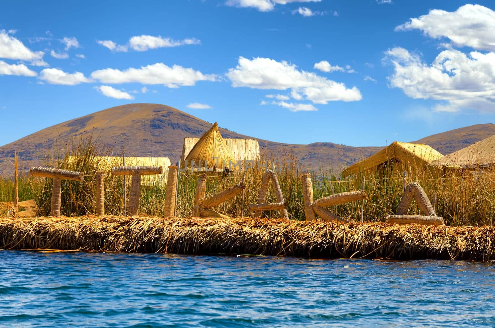 Manmade floating island with a sign spelling out Titikaka on Lake Titicaca in Peru