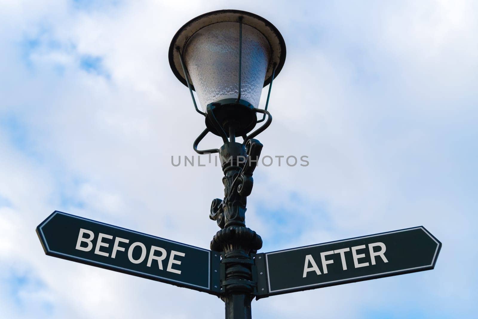 Street lighting pole with two opposite directional arrows over blue cloudy background. Before versus After concept.
