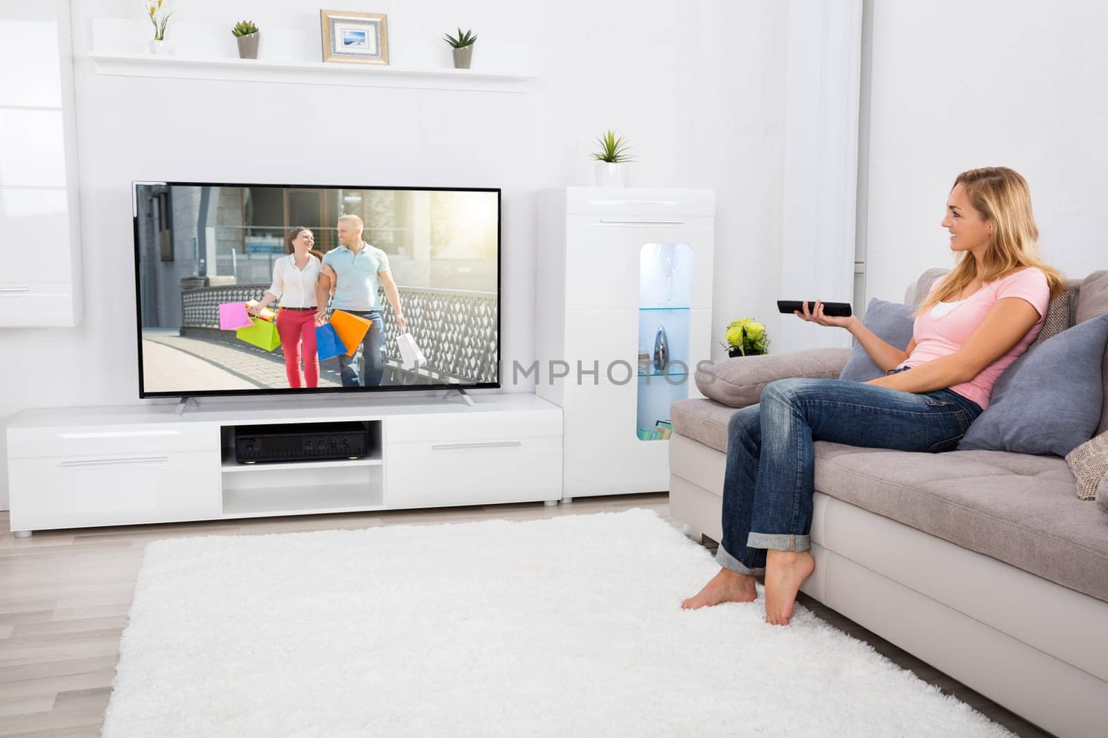 Young Happy Woman Sitting On Couch Watching Romantic Movie On Television At Home