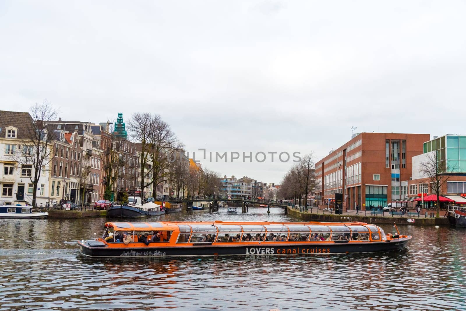 Amsterdam, Netherlands - January 9, 2017: Street view with traditional Dutch row houses and famous canals in Amsterdam historical city center, the Netherlands’ capital, known for its artistic heritage