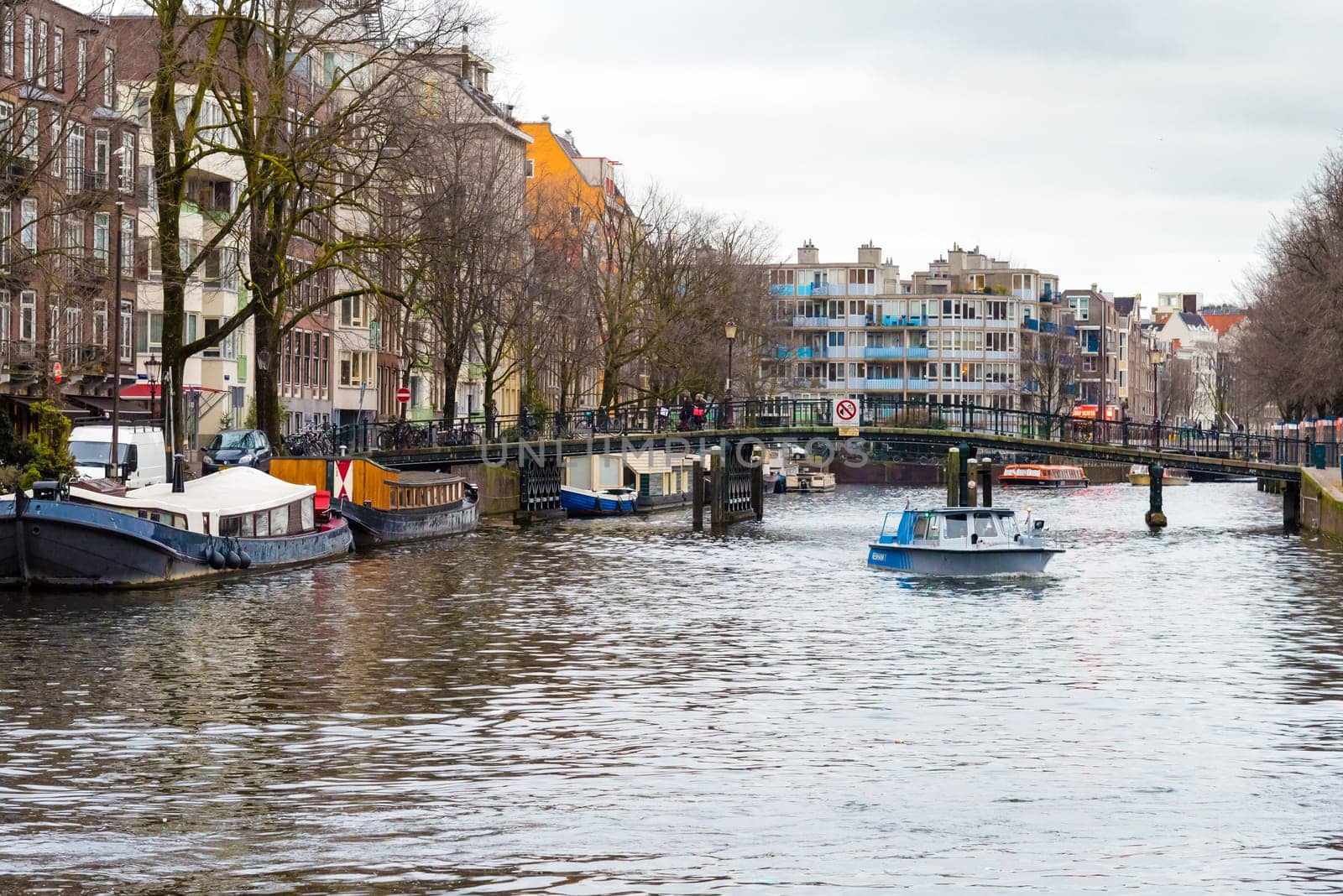 Amsterdam, Netherlands - January 9, 2017: Street view with traditional Dutch row houses and famous canals in Amsterdam historical city center, the Netherlands’ capital, known for its artistic heritage