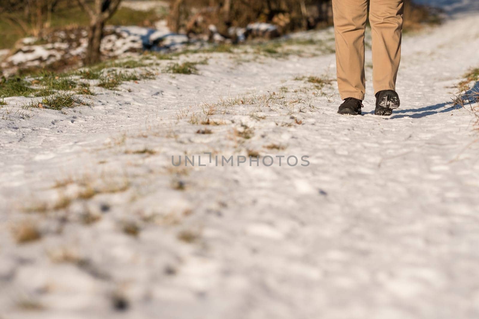Feet with black shoes in the snow on a dirt road