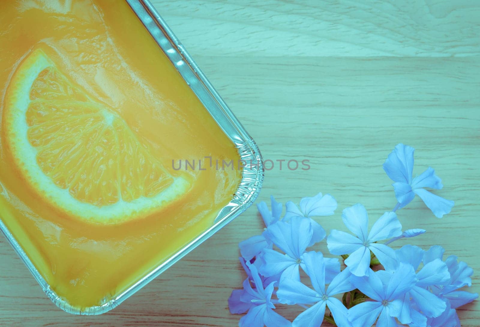 Orange soft cake with sliced orange fruit in aluminum foil tray on wooden background. Retro-Vintage filter effect